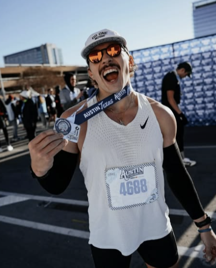 Lachende hardloper in witte sportkleding met medaille en startnummer 4688 na de Austin Marathon.