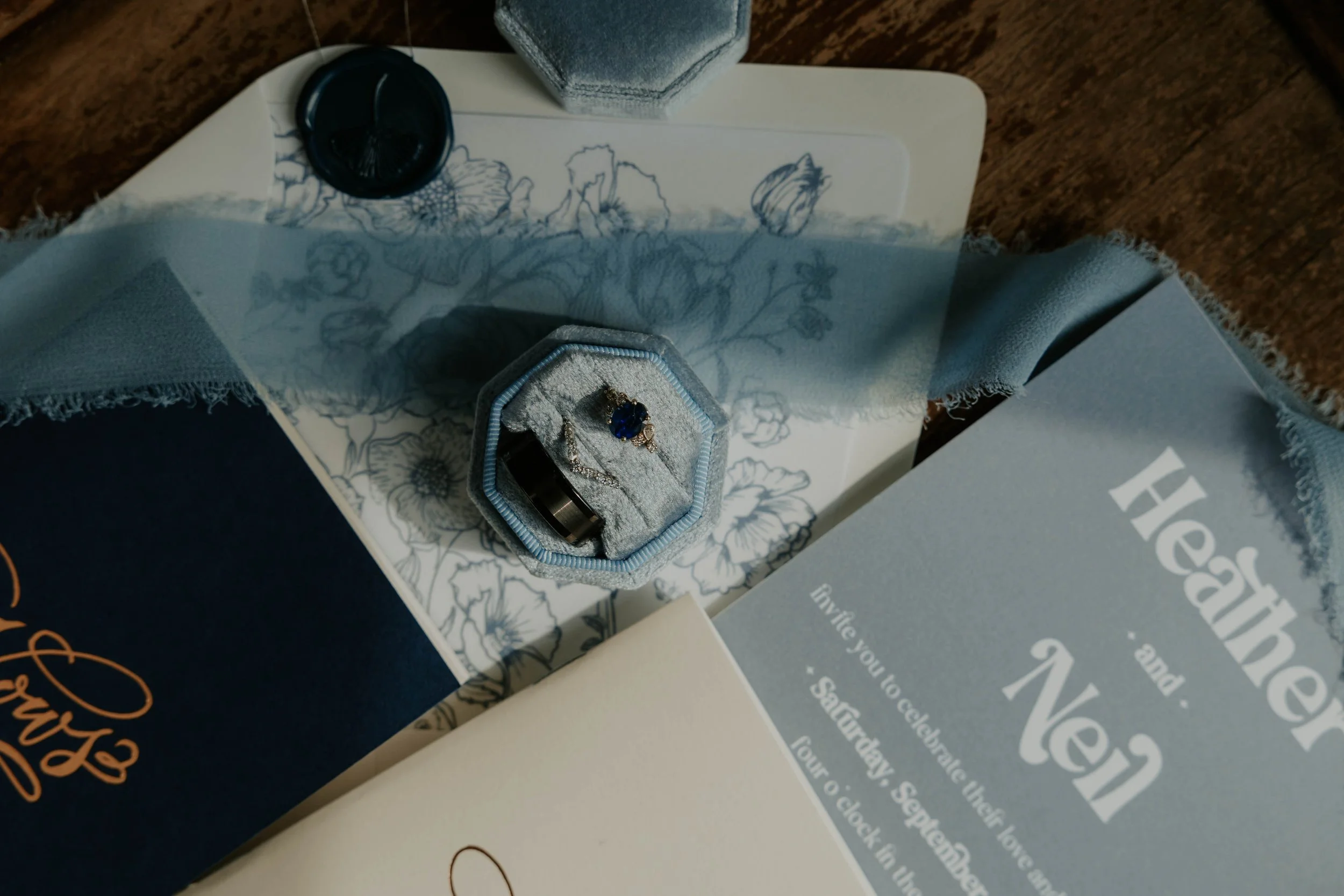 A jewelry box with a ring and a necklace, placed on a surface with decorative paper and surrounded by sales or promotional materials.