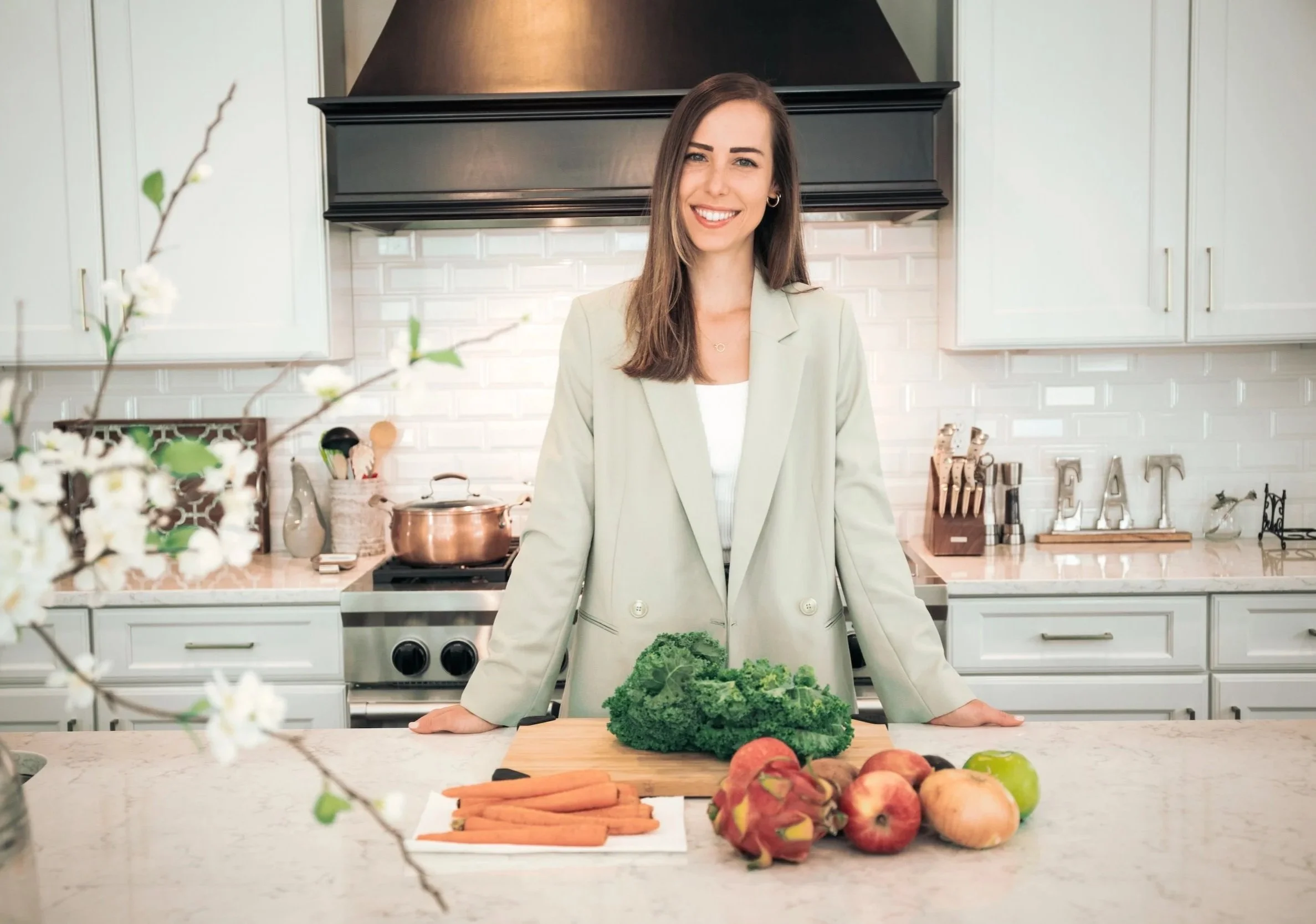 Registered Dietitian standing in a bright kitchen with fresh fruits and vegetables.