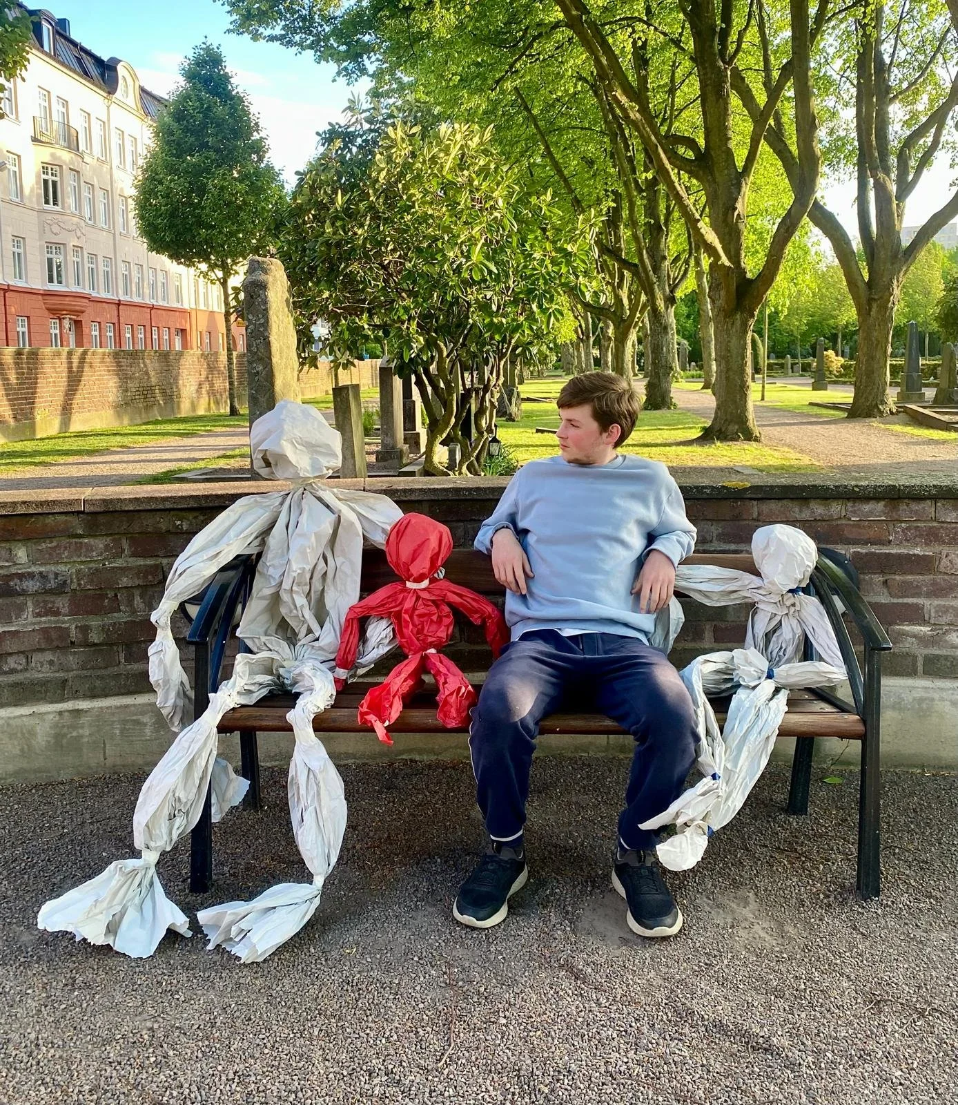 A boy on a bench with life-size paper puppets