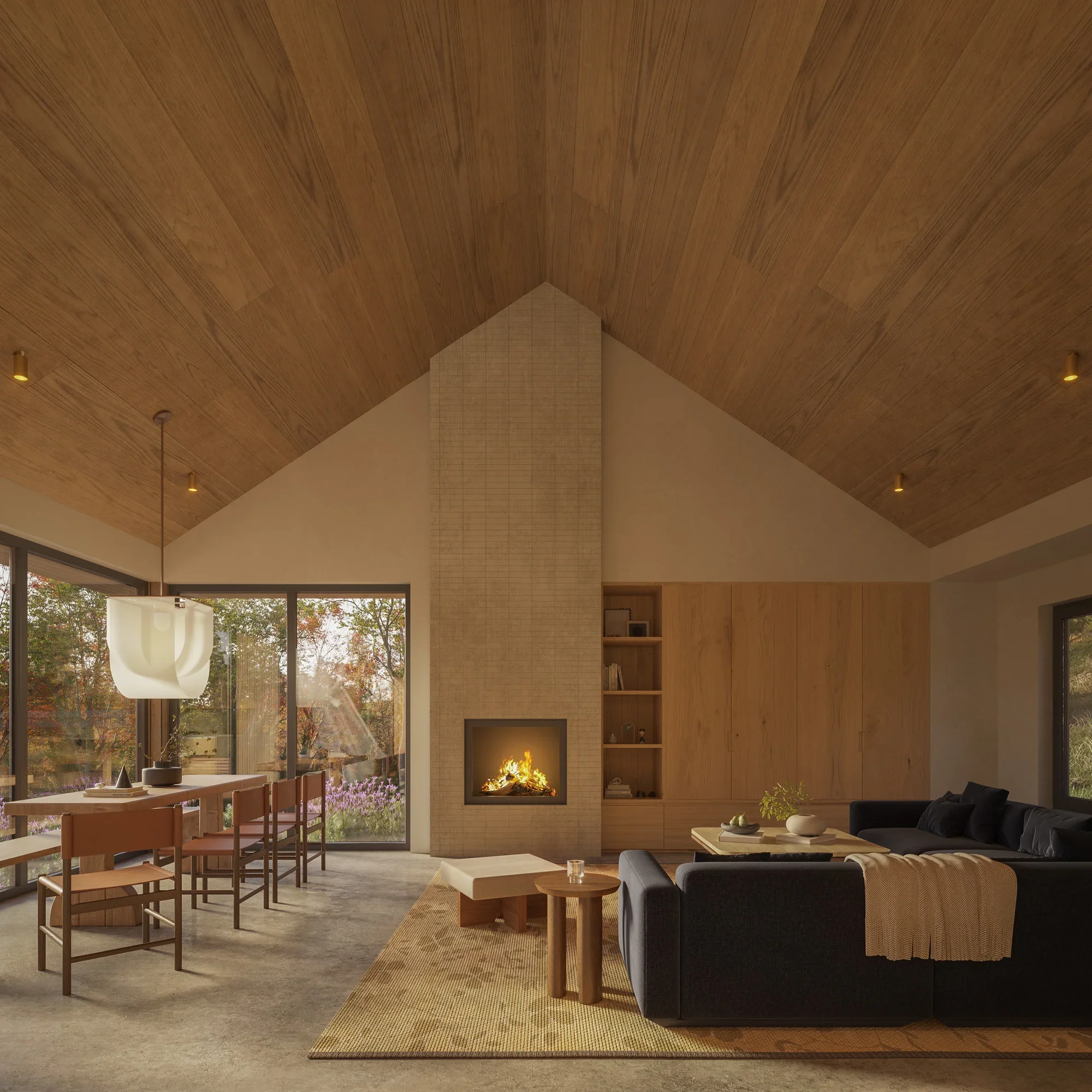 Living room with a wood ceiling, a fireplace, a black sofa, a beige armchair, a wooden coffee table, a dining area with wooden chairs, large windows showing trees outside, a hanging light fixture, and a beige rug.
