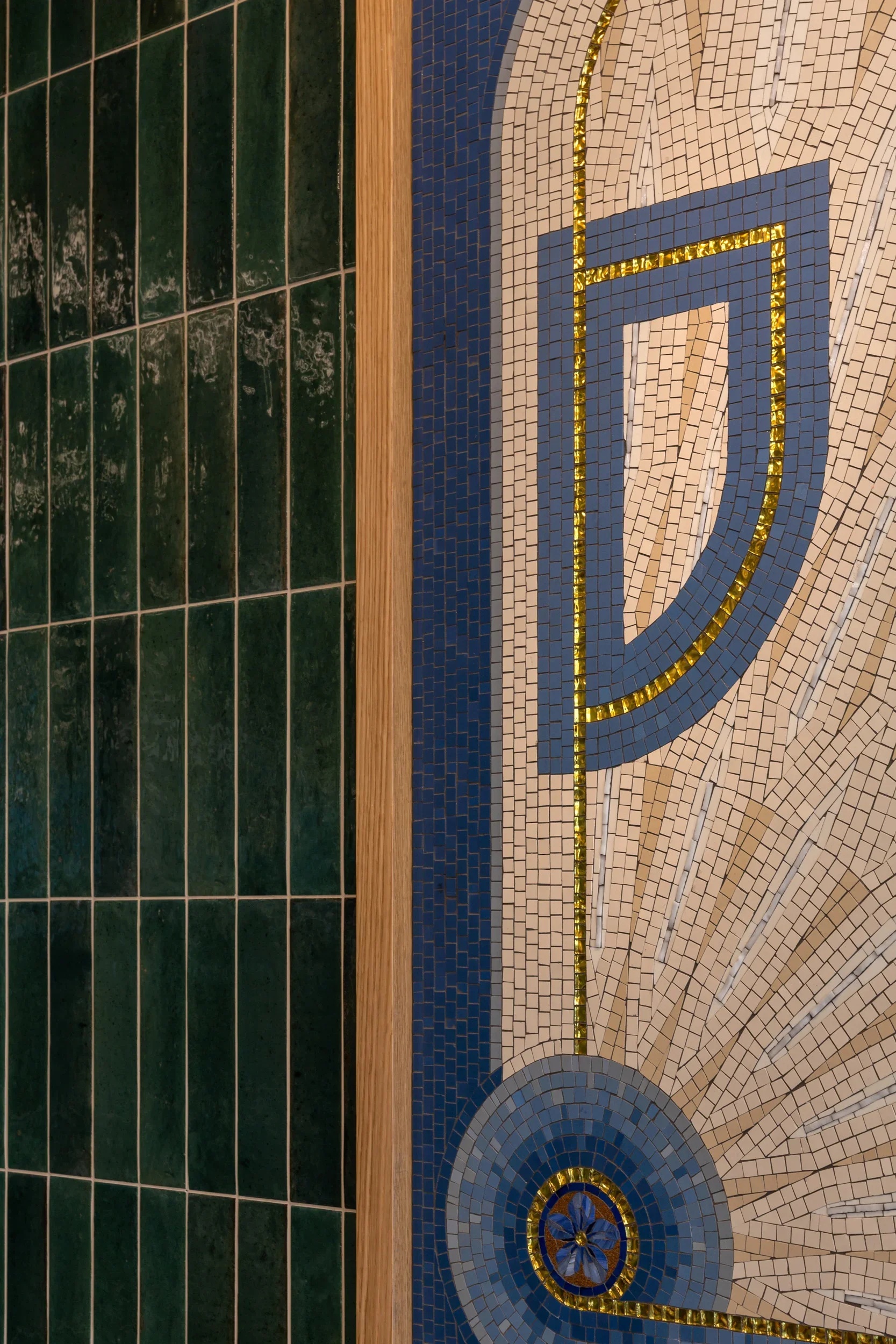 Close-up of decorative mosaic on wall, featuring blue, white, and gold tiles but no clear object or scene.