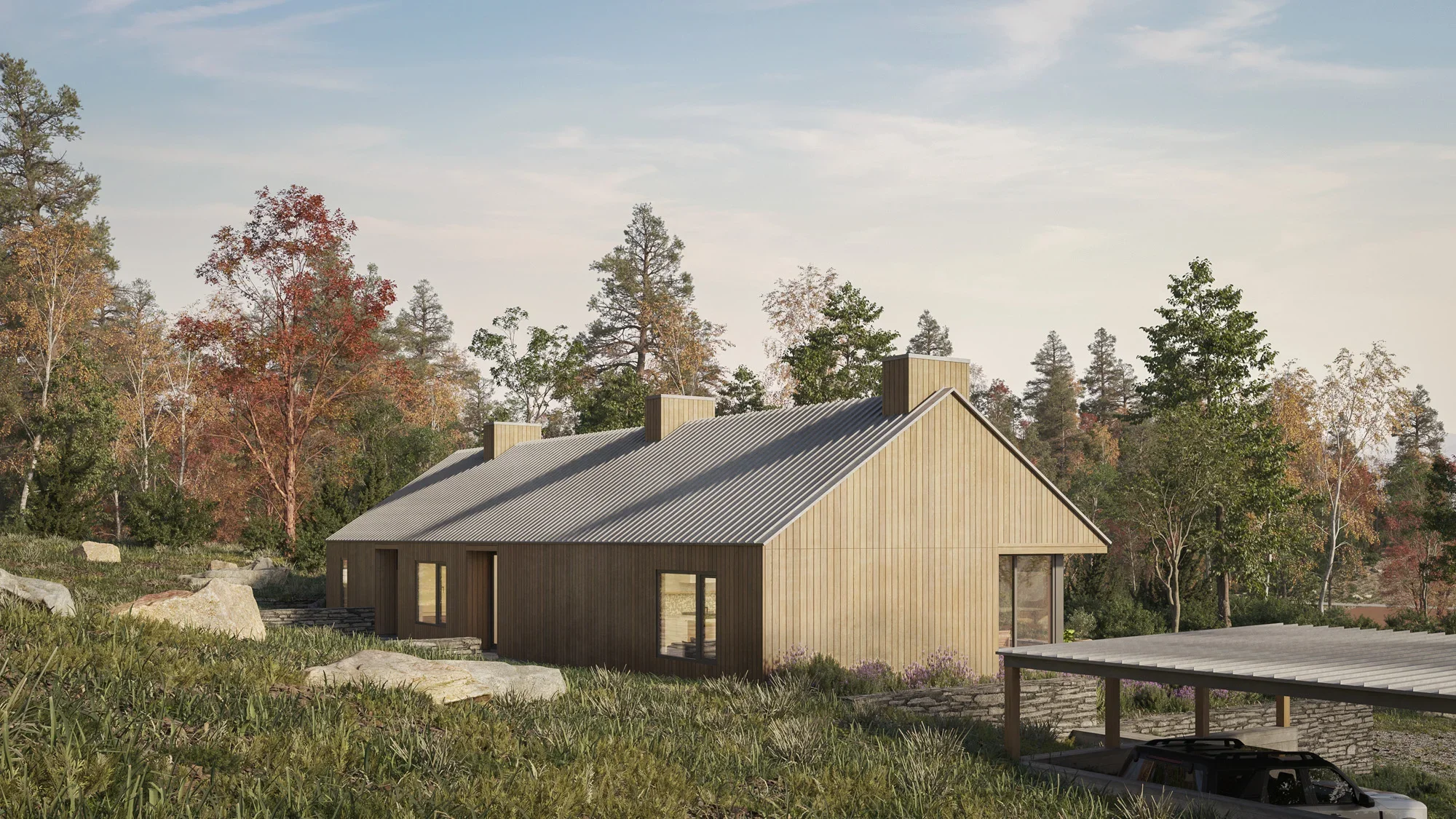 Modern wooden house with a metal roof surrounded by trees with fall foliage and rocks, under a partly cloudy sky.