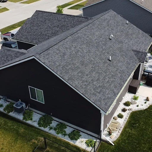 Aerial view of a black house with a grey shingle roof in a residential neighborhood.
