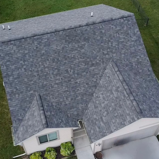 Aerial view of a house with a gray shingle roof and a backyard with grass.