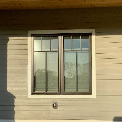 A window with metal security bars on the outside of a beige house with horizontal siding.
