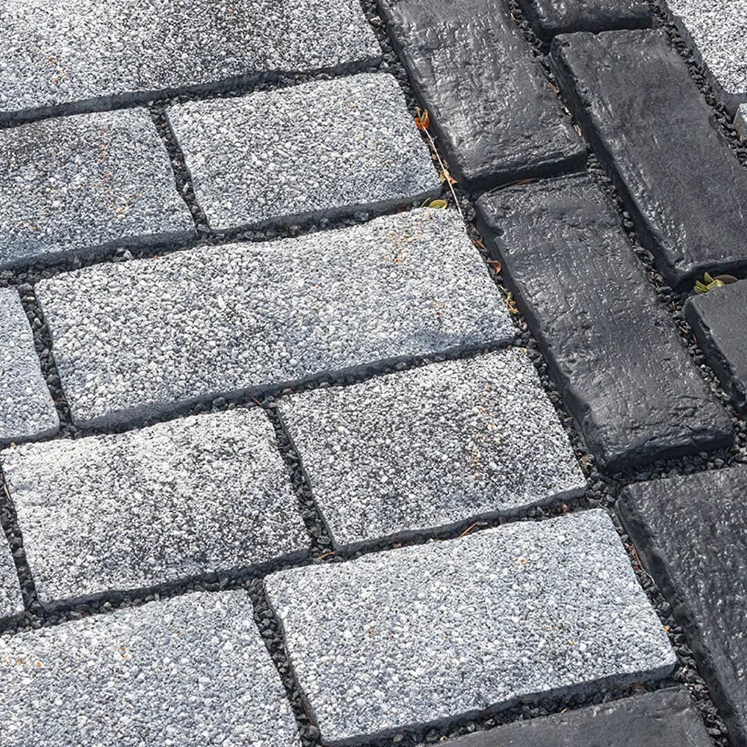 Close-up of a cobblestone sidewalk featuring a combination of light gray and dark gray stones with mortar in between.