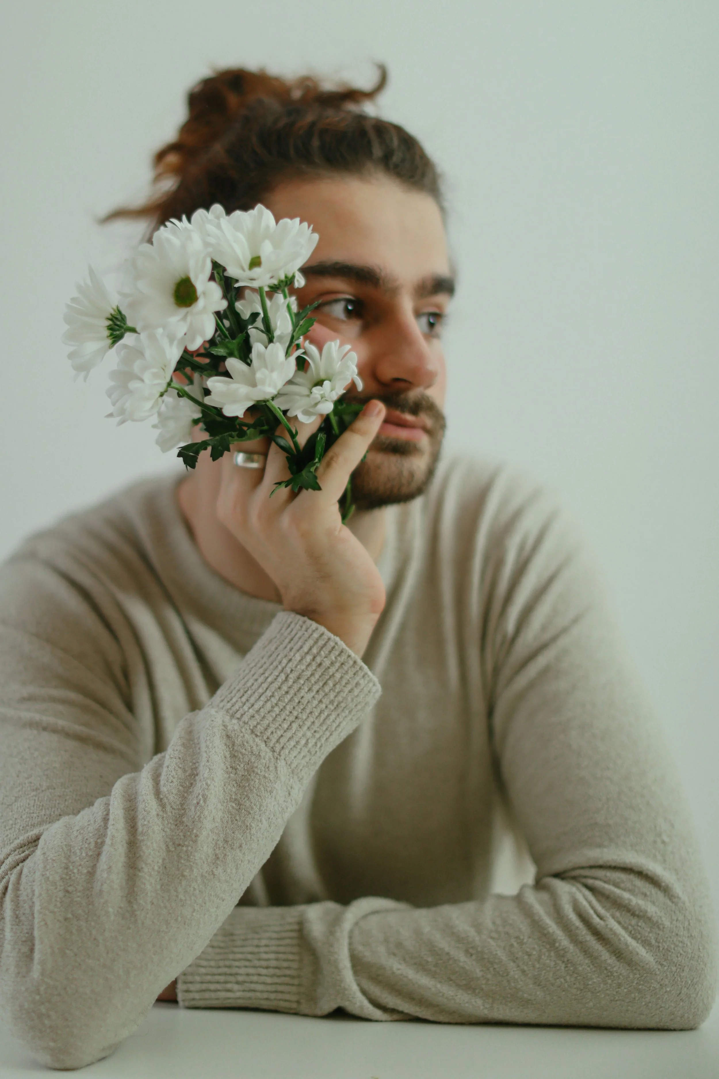 Man holding white daisies near his face, representing the adults Megan Ethridge supports in therapy