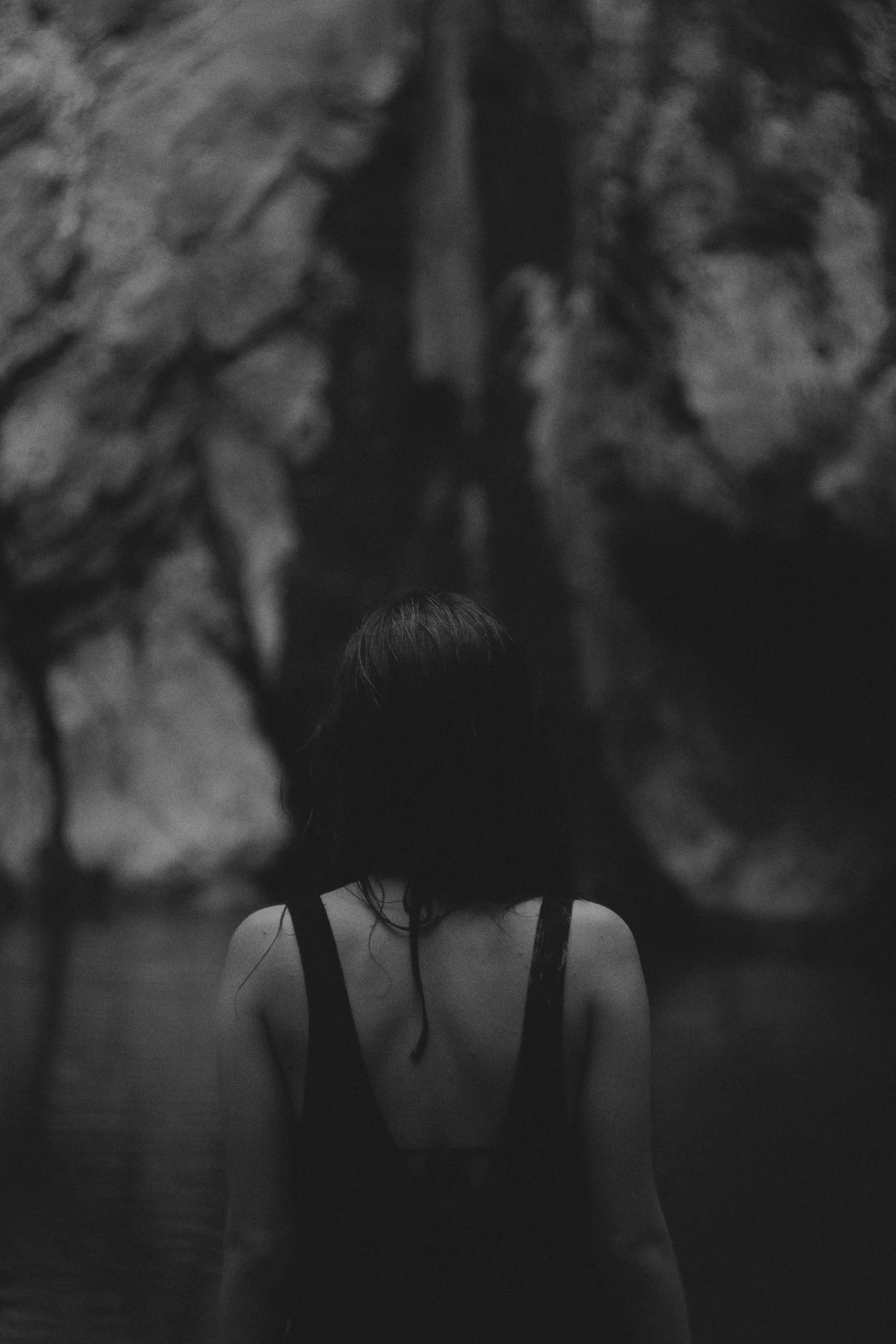 Woman seen from behind in soft, dim light, representing body-based somatic therapy