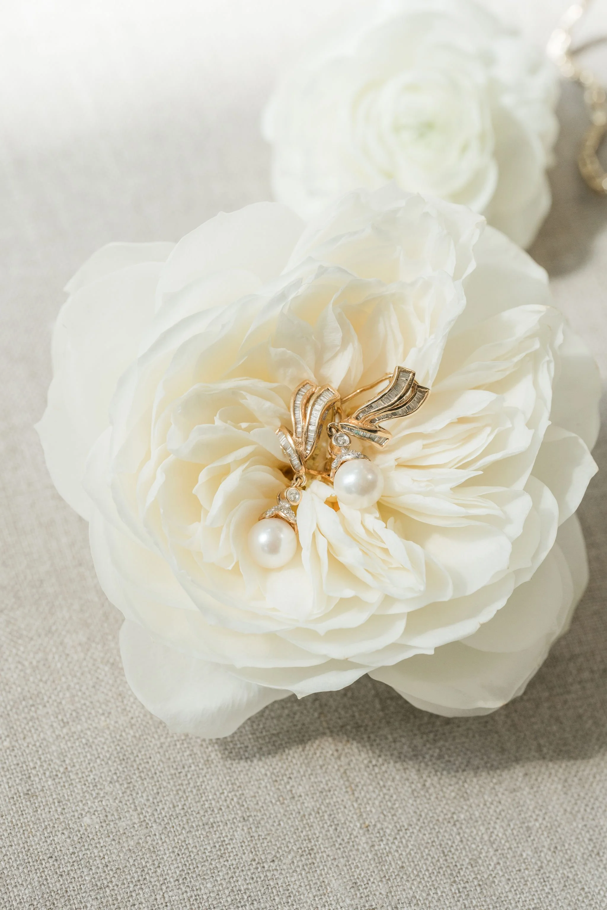 Close-up of white flowers with gold and pearl jewelry on top