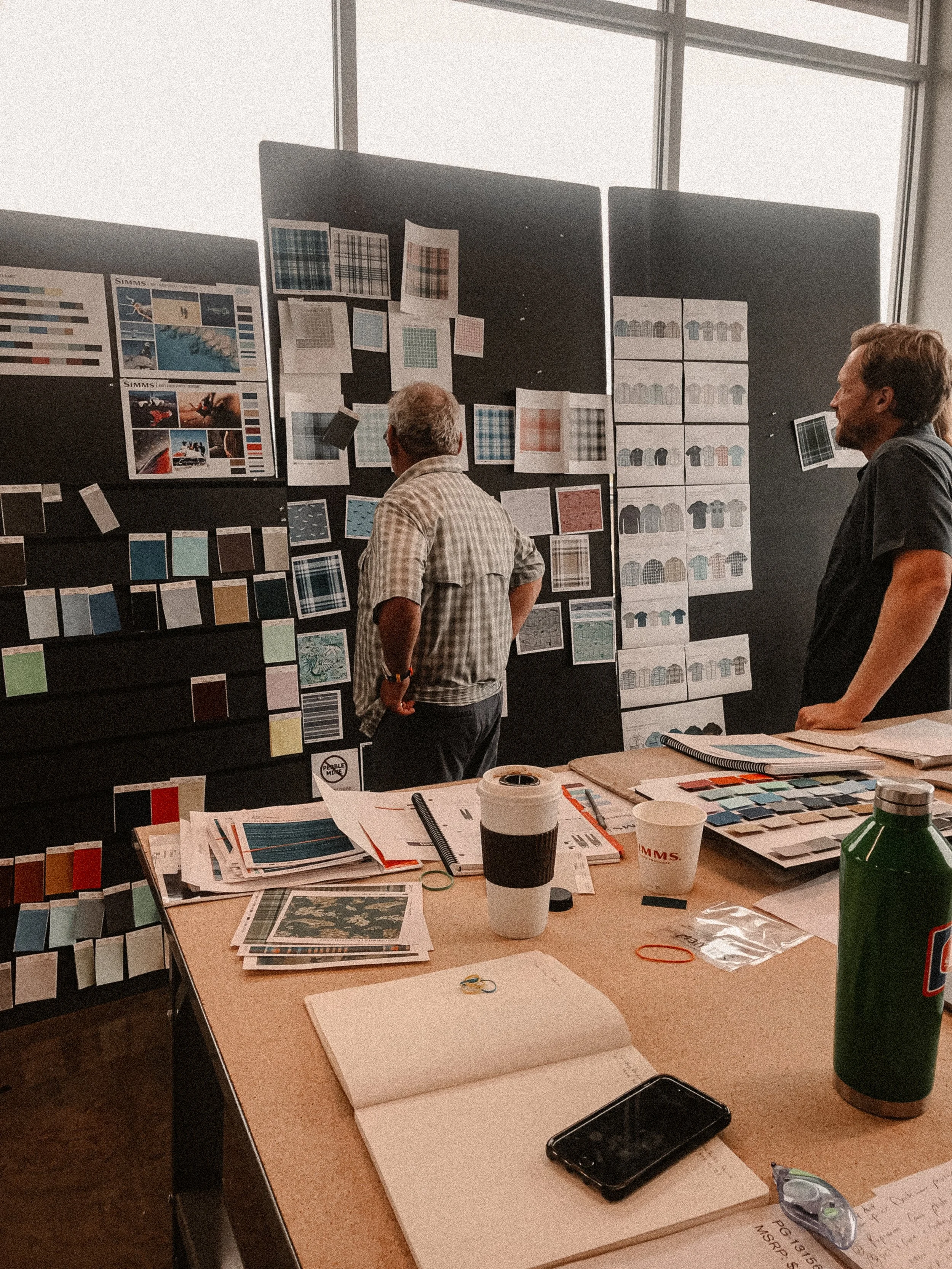 Designers reviewing textile patterns, color swatches, and mood boards in Simms Fishing studio in Bozeman, Montana