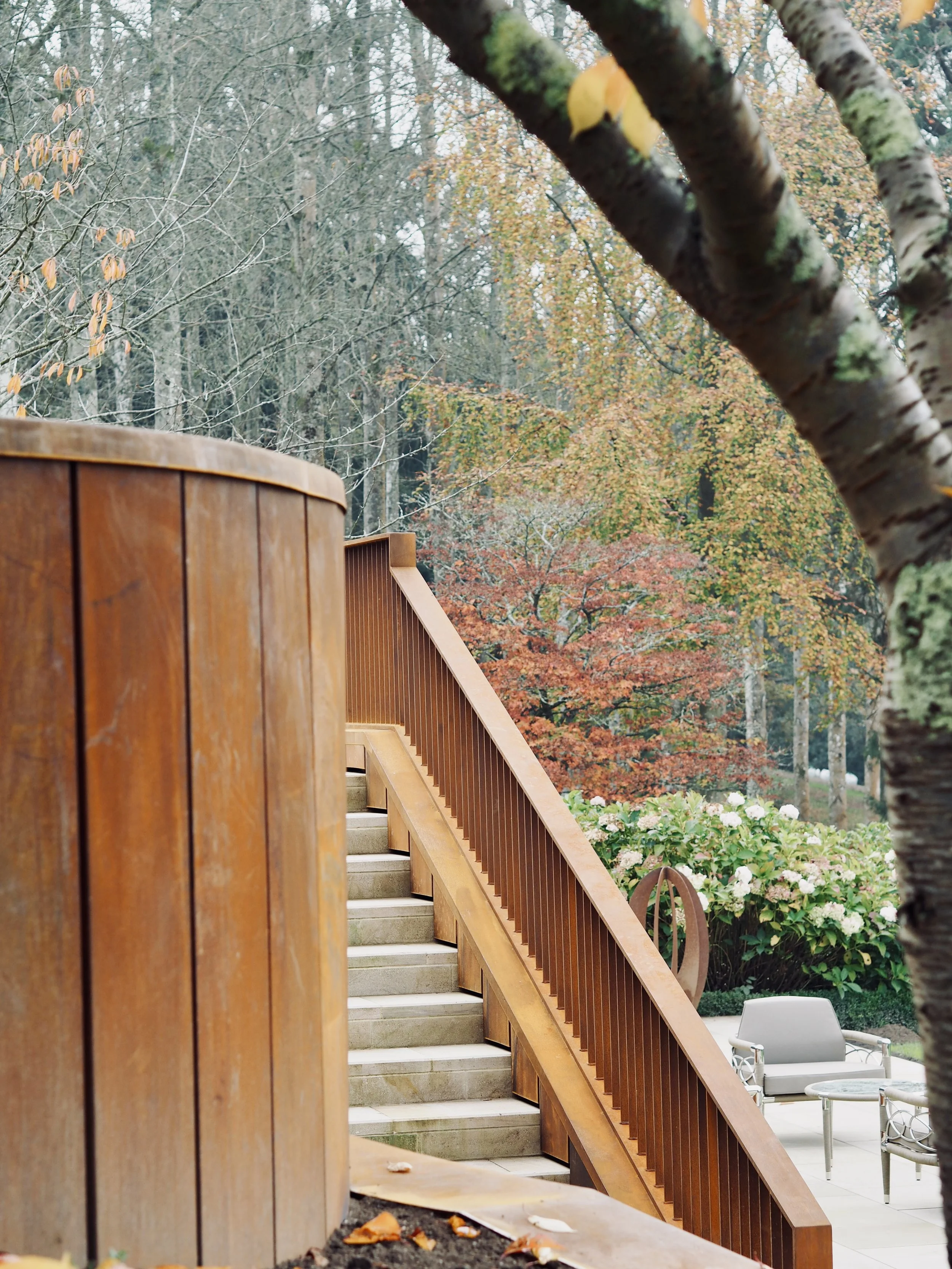 Curved Corten steel cladding and stair balustrade beside mature trees at Rotherfield.