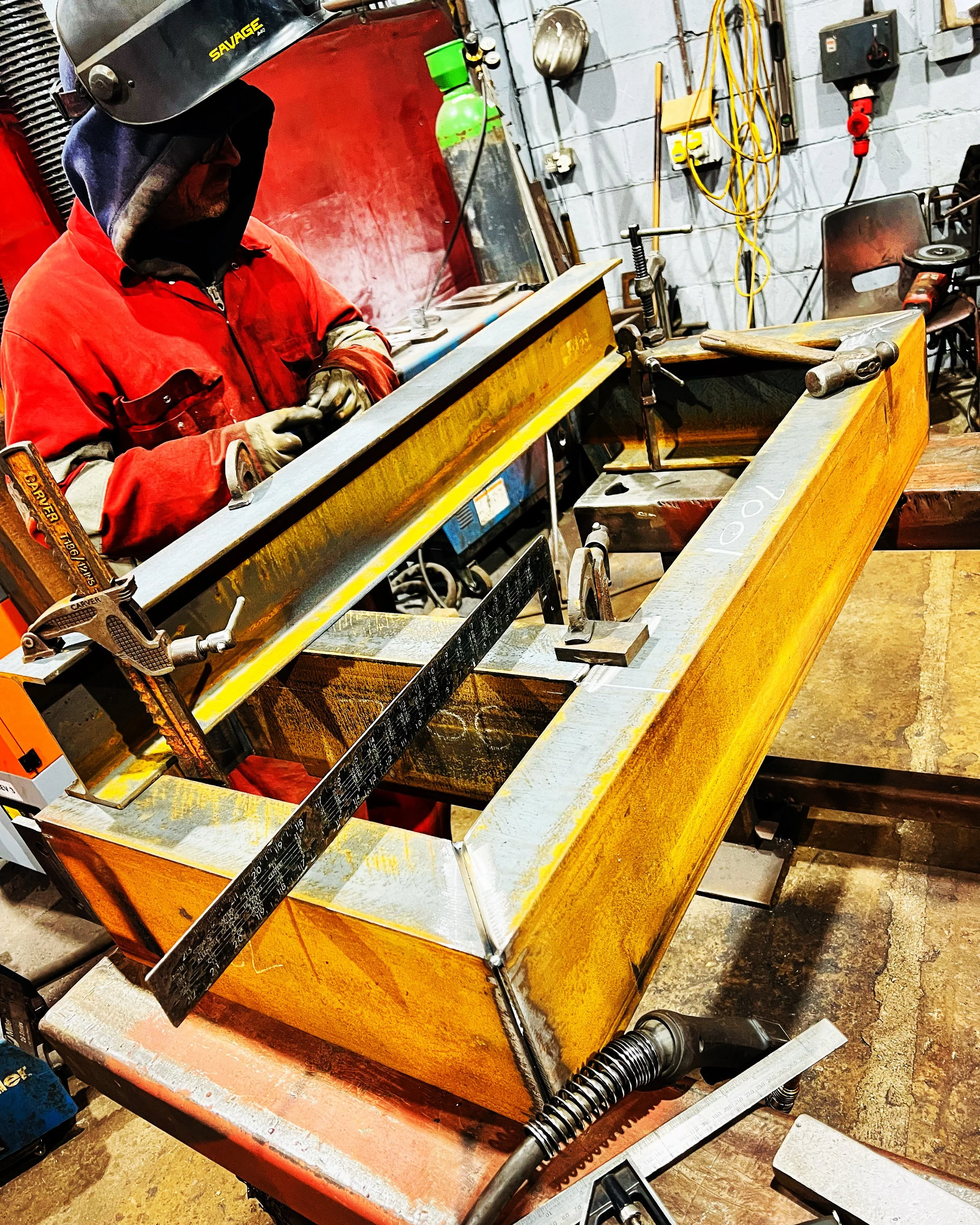 Fabricator welding a steel component in the workshop.