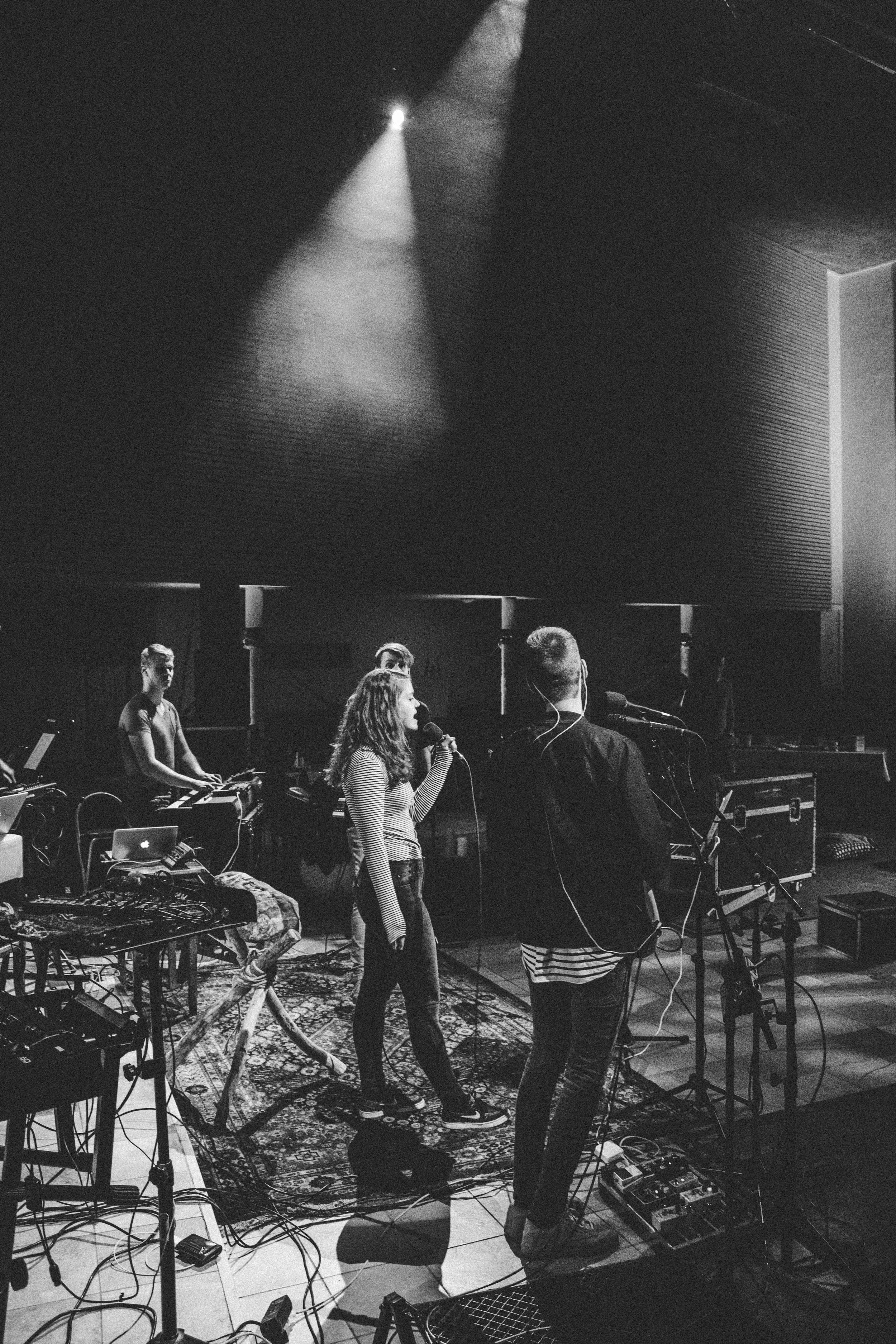 Singer leading a live band rehearsal on stage, black and white