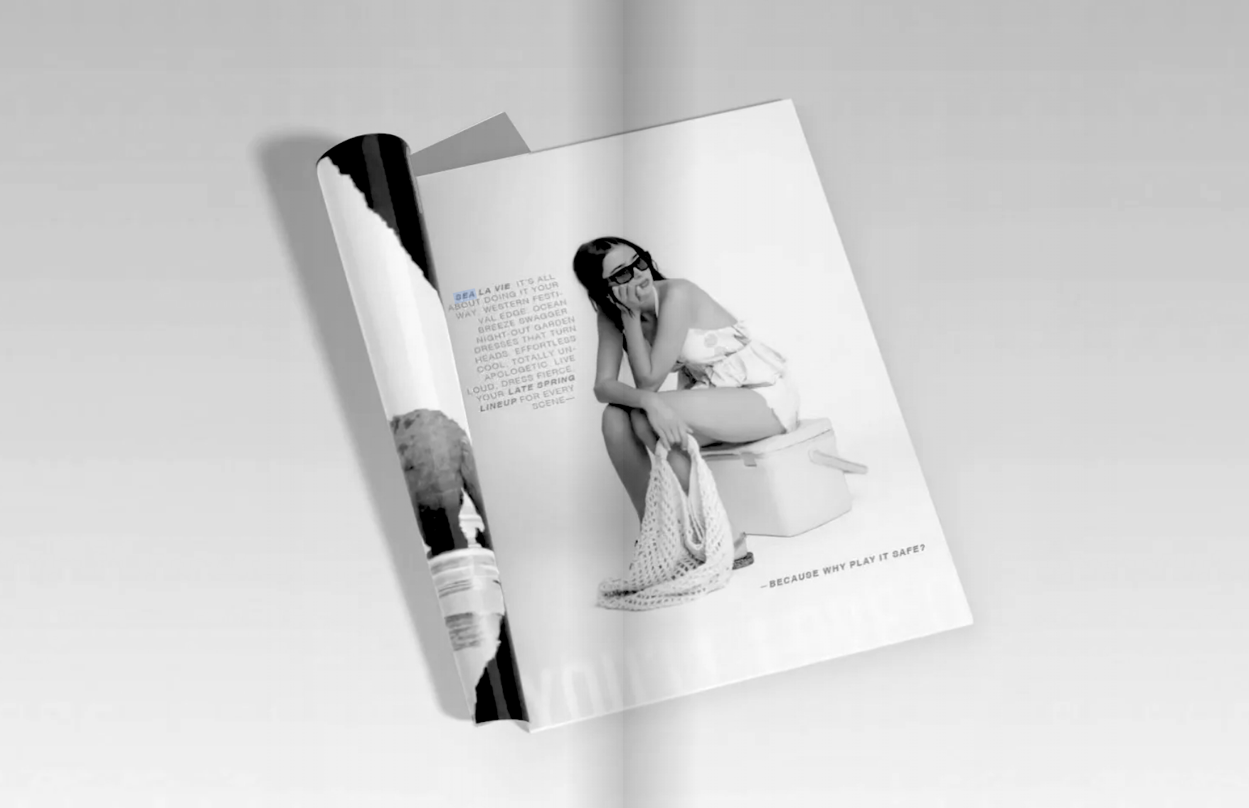 A black and white photo of a magazine open to a fashion photo spread featuring a woman sitting on a toilet with glasses, a top, and shorts, holding a bag and wearing a plaid shirt. The page includes text about the fashion and a caption at the bottom 