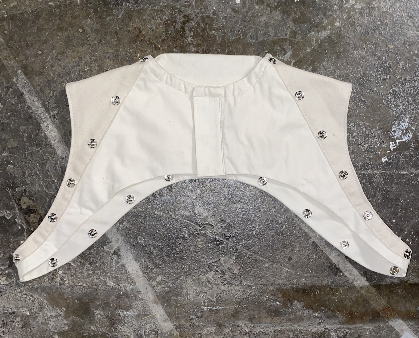 White garment with silver embellishments on a rough, textured gray surface.
