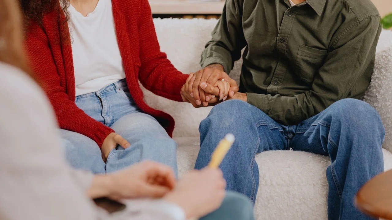 Couples holding hands working through communication struggles in relationship therapy.