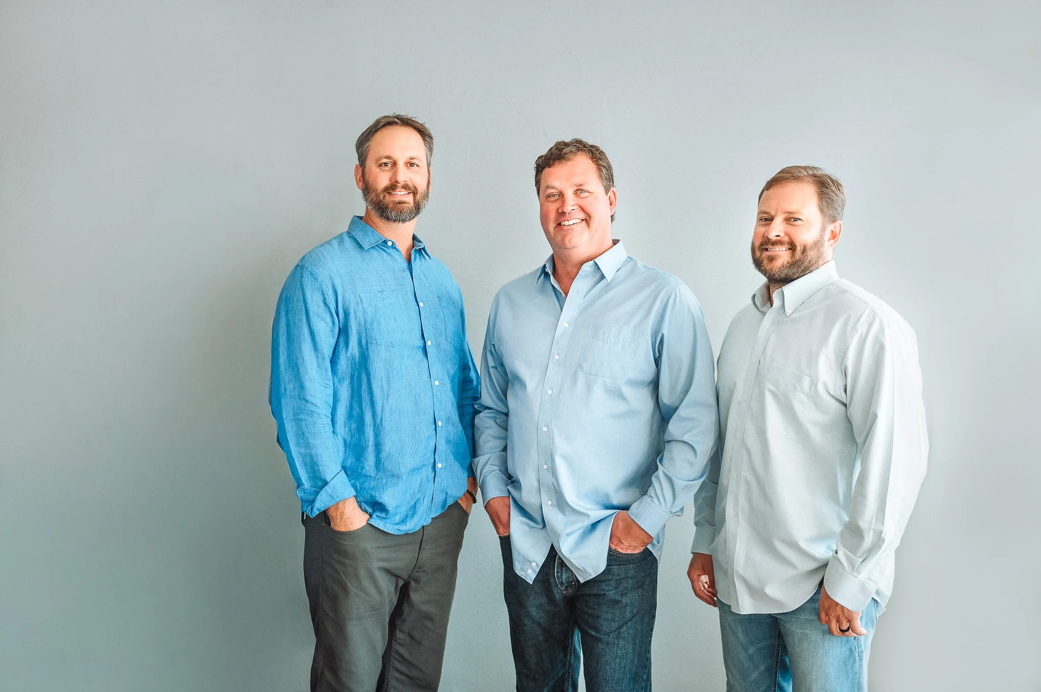 Latitude 29 Group standing together against a light gray wall, all wearing collared shirts and smiling.
