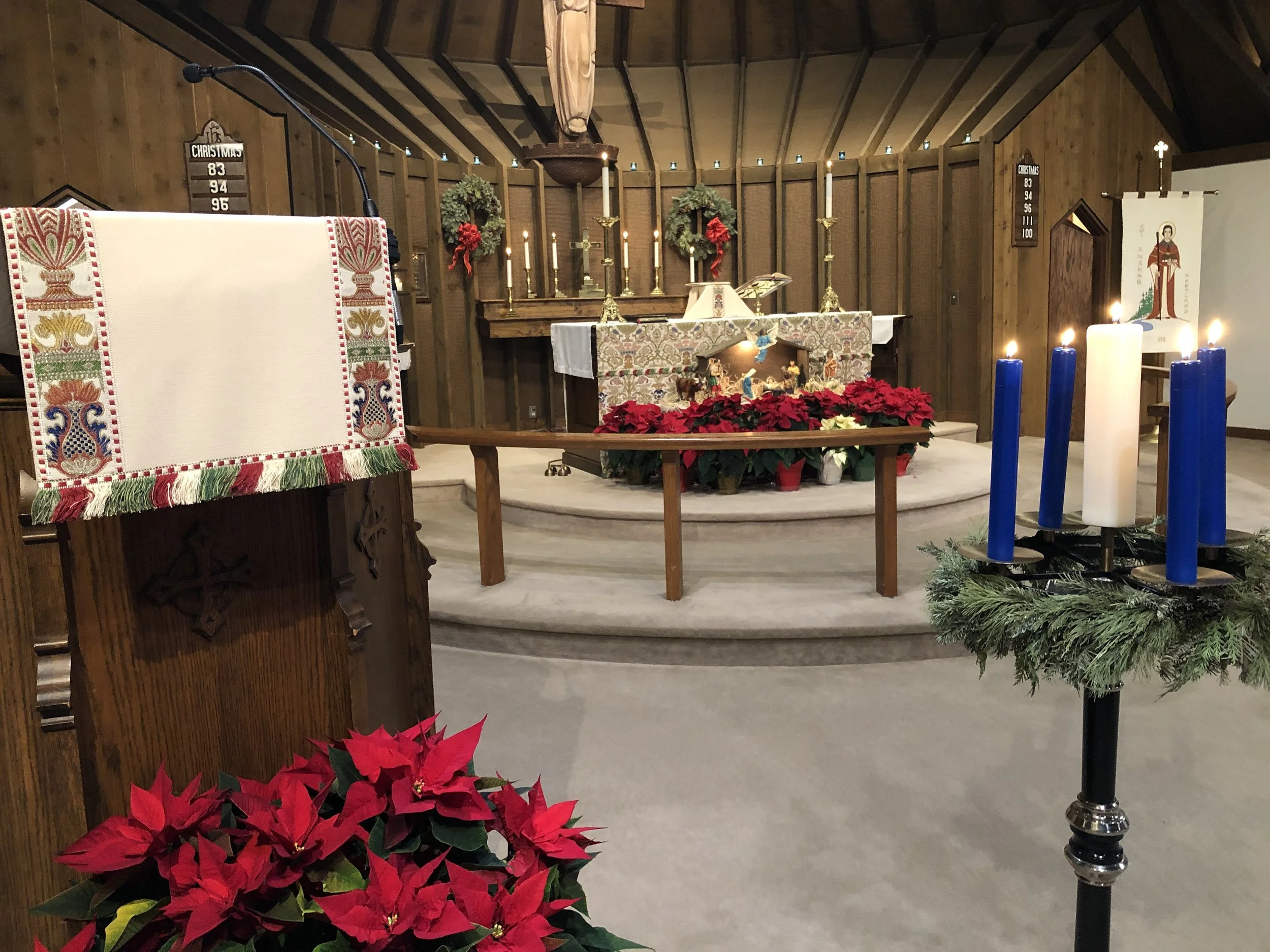 St. Anskar’s sanctuary decorated with poinsettias, greenery, and candles during Advent.