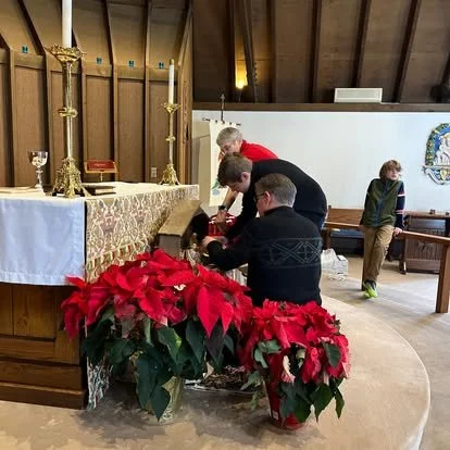 Parishioners gather near the Christmas altar decorated with red poinsettias at St. Anskar's Episcopal Church in Hartland, Wisconsin.