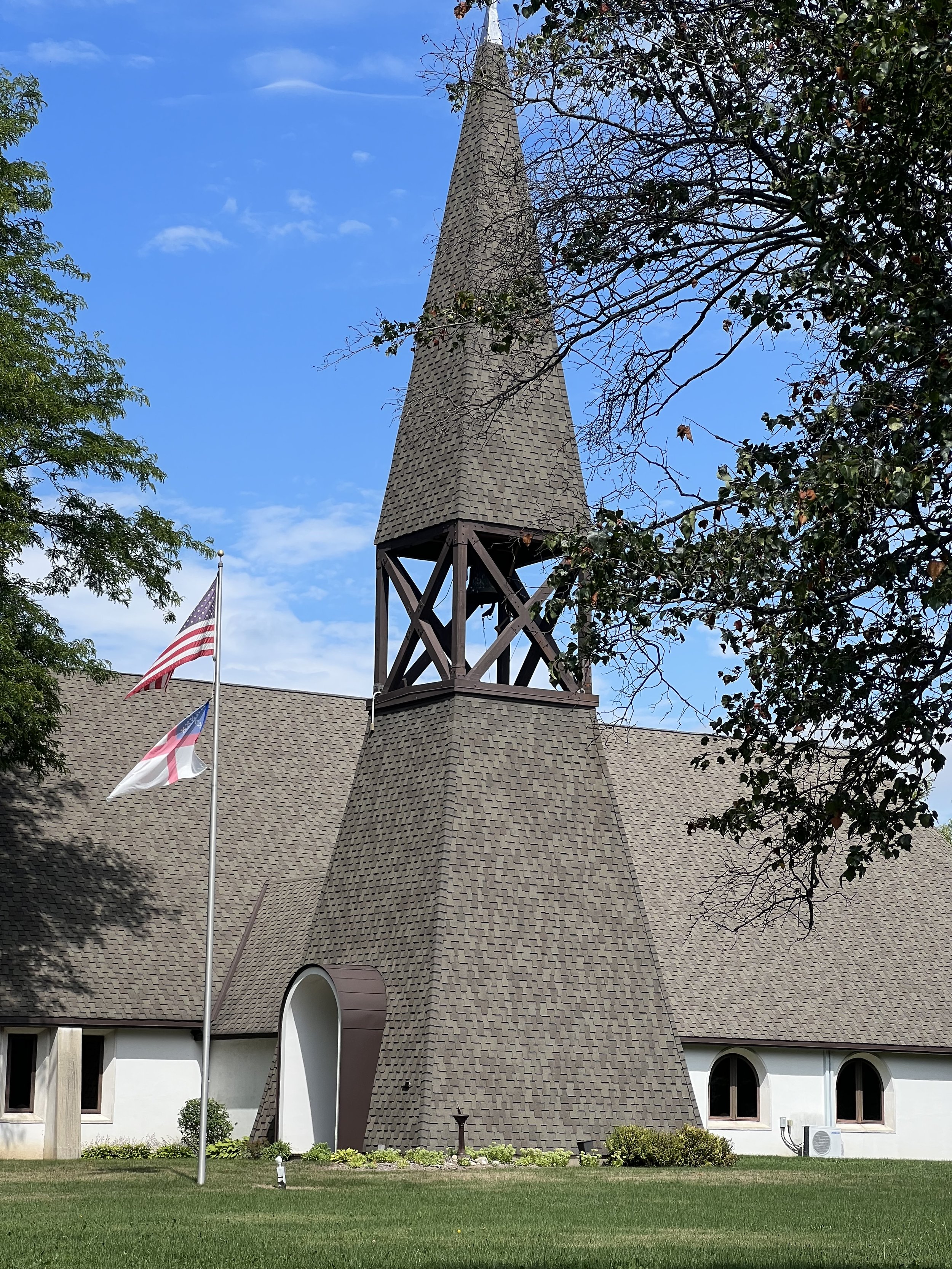 Exterior of St. Anskar’s Episcopal Church in Hartland, Wisconsin, with its distinctive steeple and landscaped grounds.