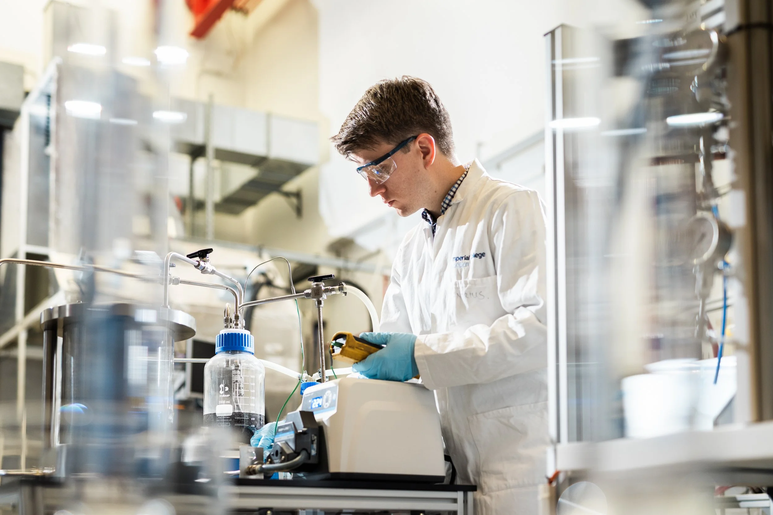 A scientist in a laboratory working with scientific equipment, wearing safety glasses and gloves.