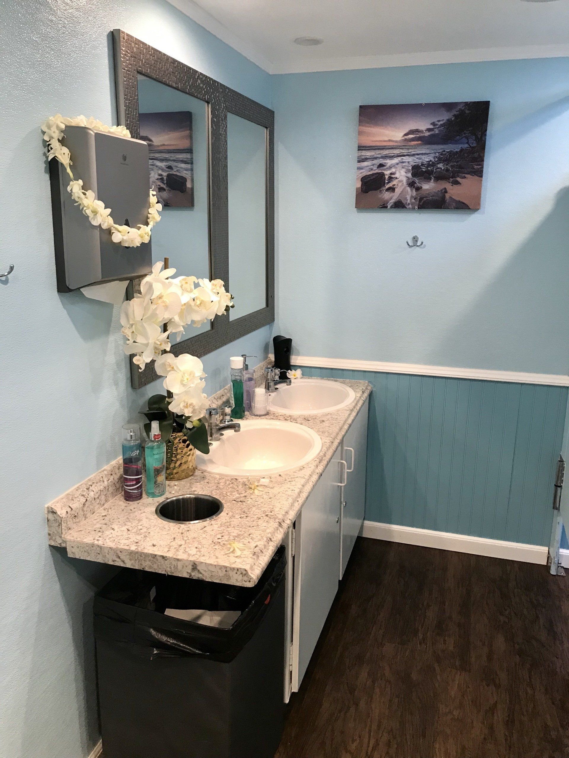 Double-sink vanity with mirrors inside an event restroom trailer suite.