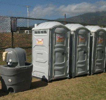 Portable toilets and a handwash station at an outdoor site.