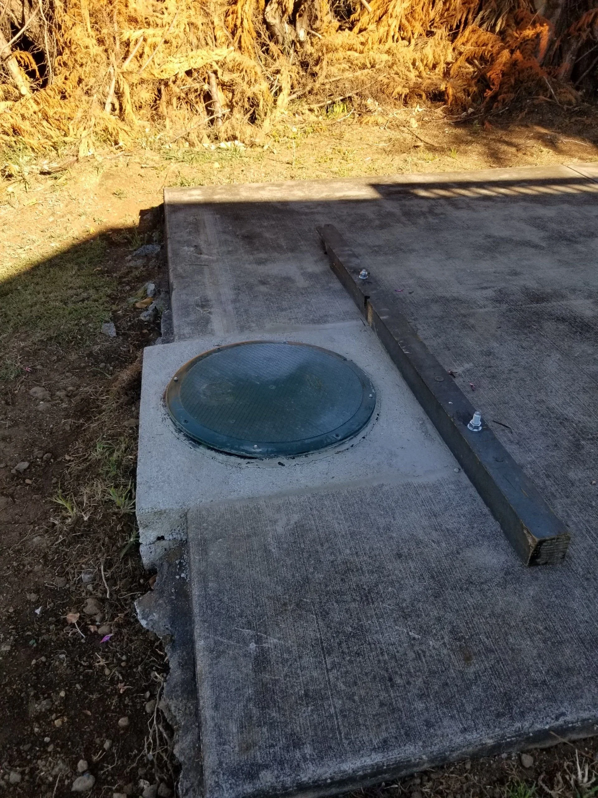 Green access cover set into a concrete pad.