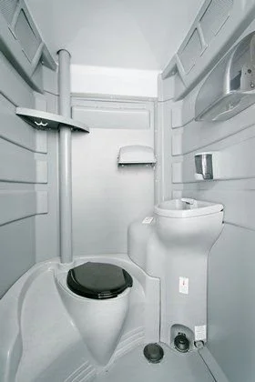 Interior of a flush portable toilet with sink and foot pedal.