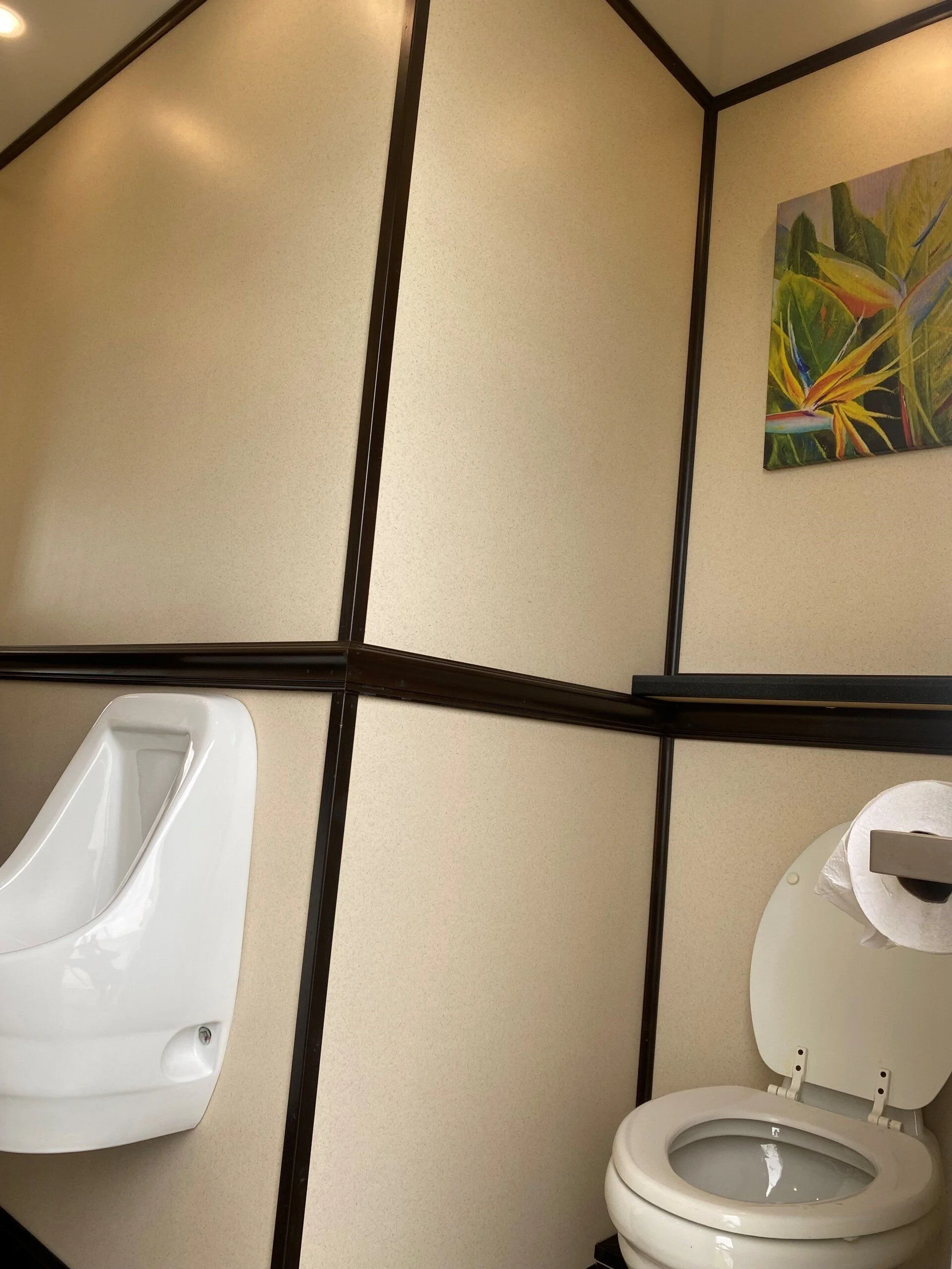 Urinals and a toilet stall in an event restroom trailer men’s suite.