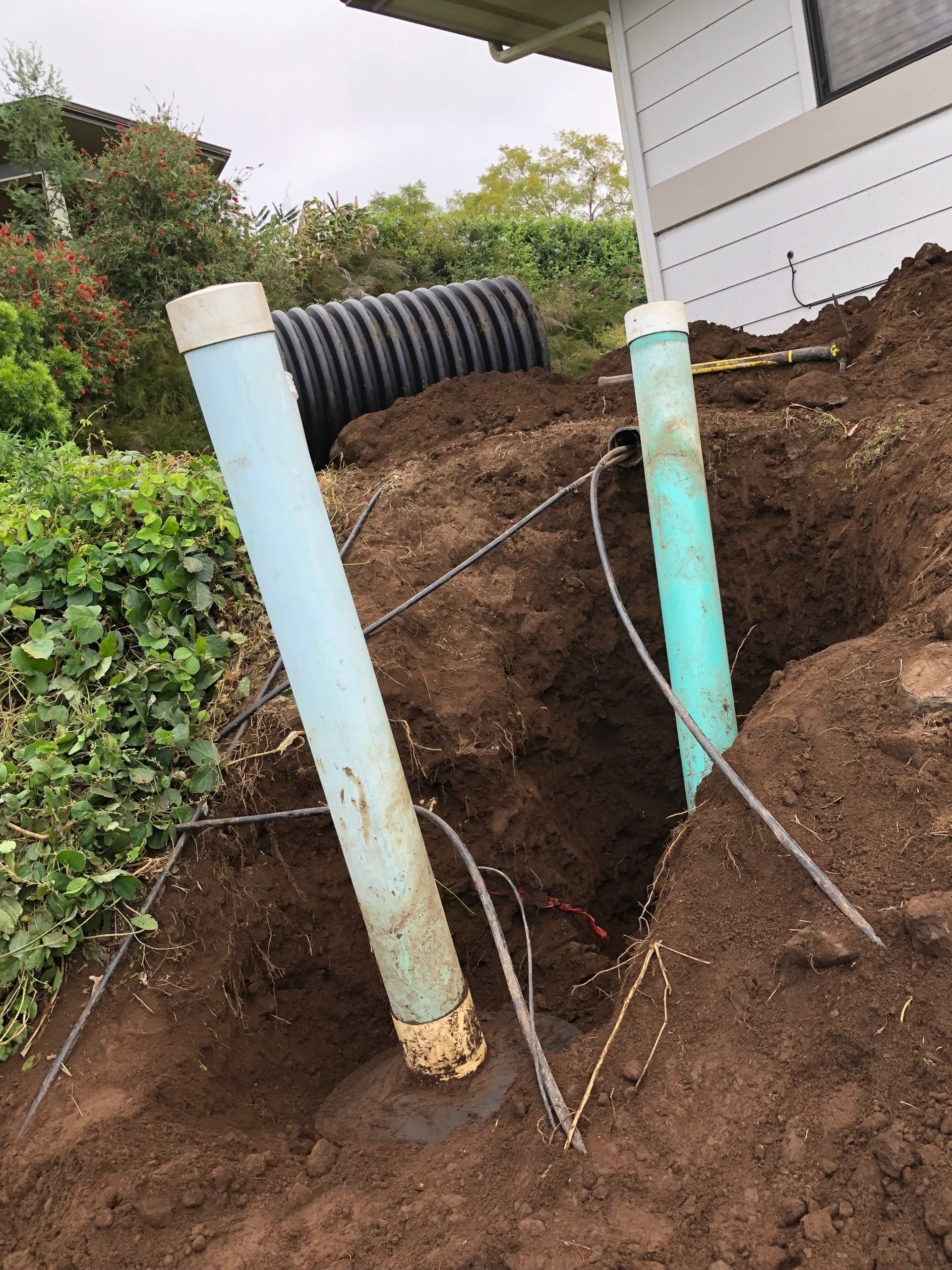 Two system pipes exposed beside a home.