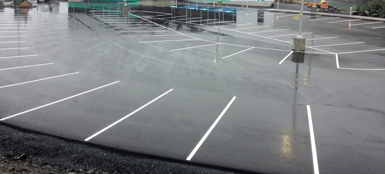 Empty parking lot on a rainy day with white parking space lines and wet pavement.