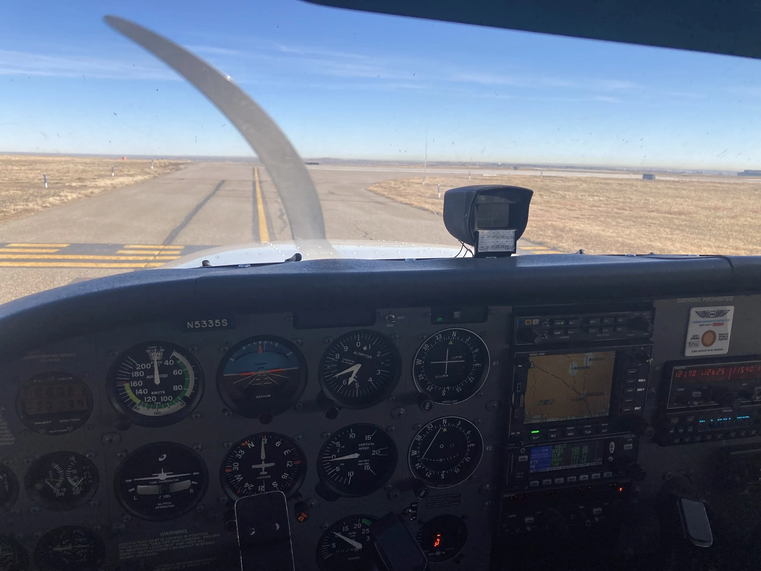 Interior view of an airplane cockpit with instruments, gauges, and controls, showing a barren landscape with a clear blue sky through the windshield.