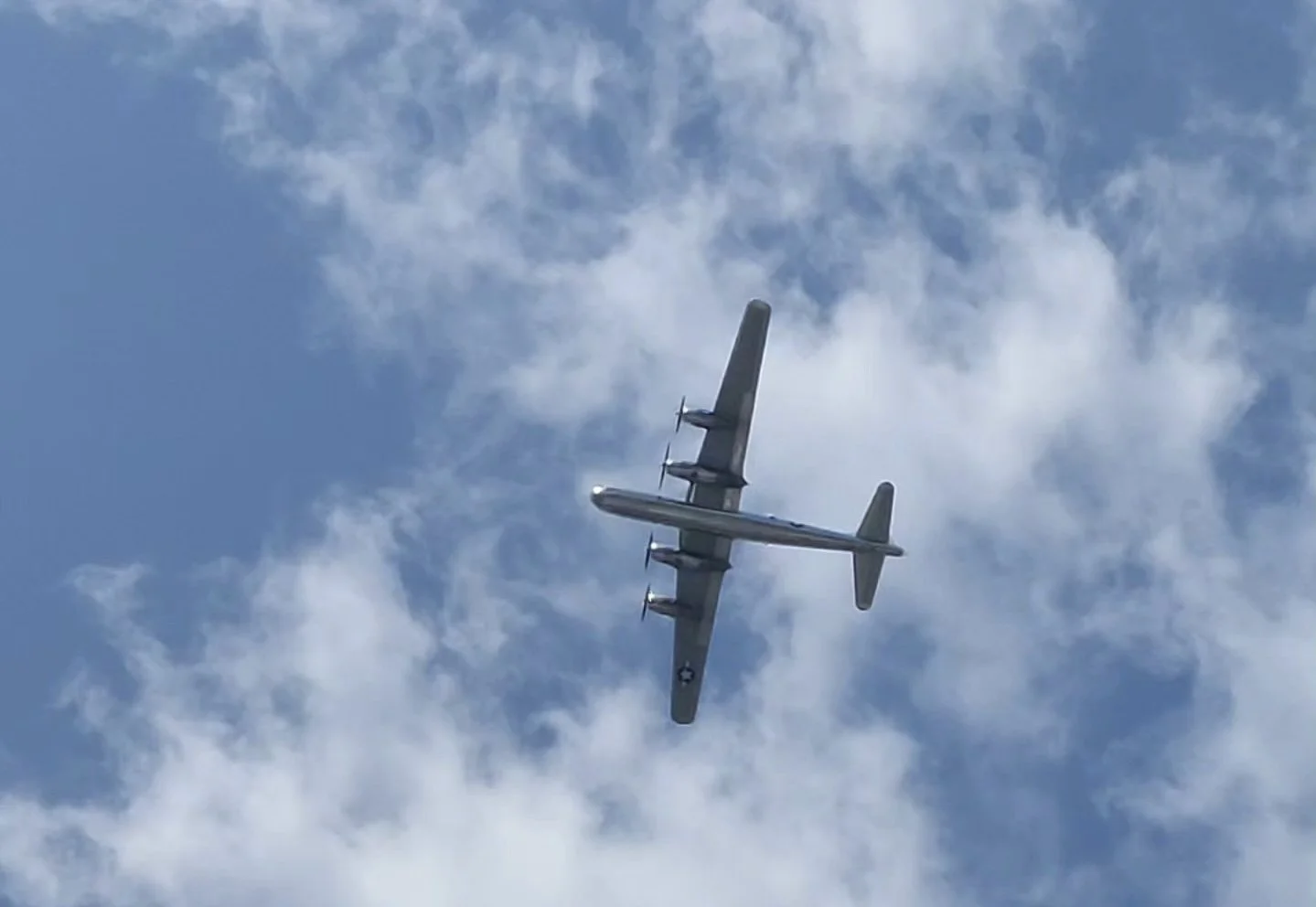 A military aircraft flying in the sky with clouds around.
