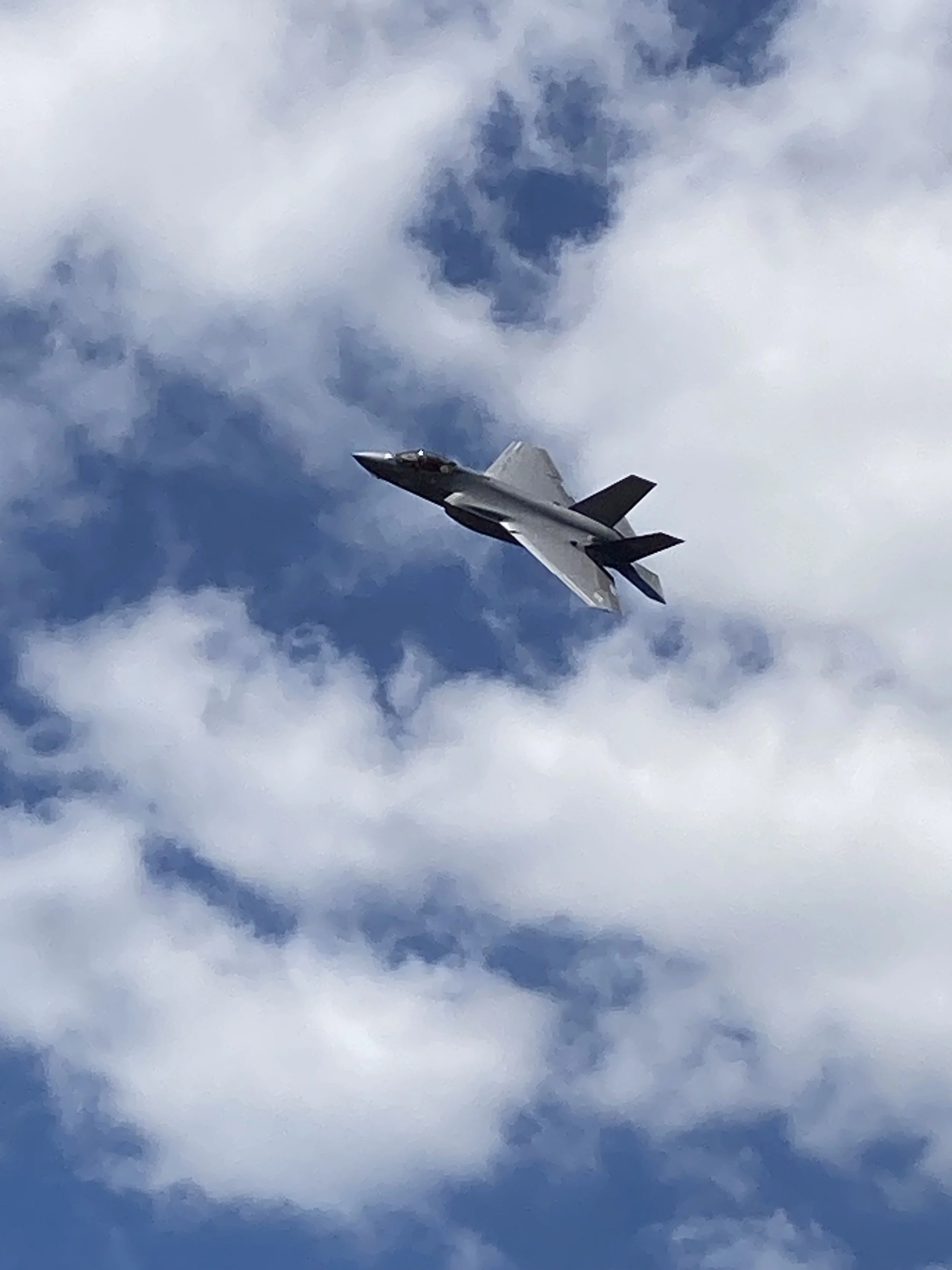 A fighter jet flying through a cloudy sky.