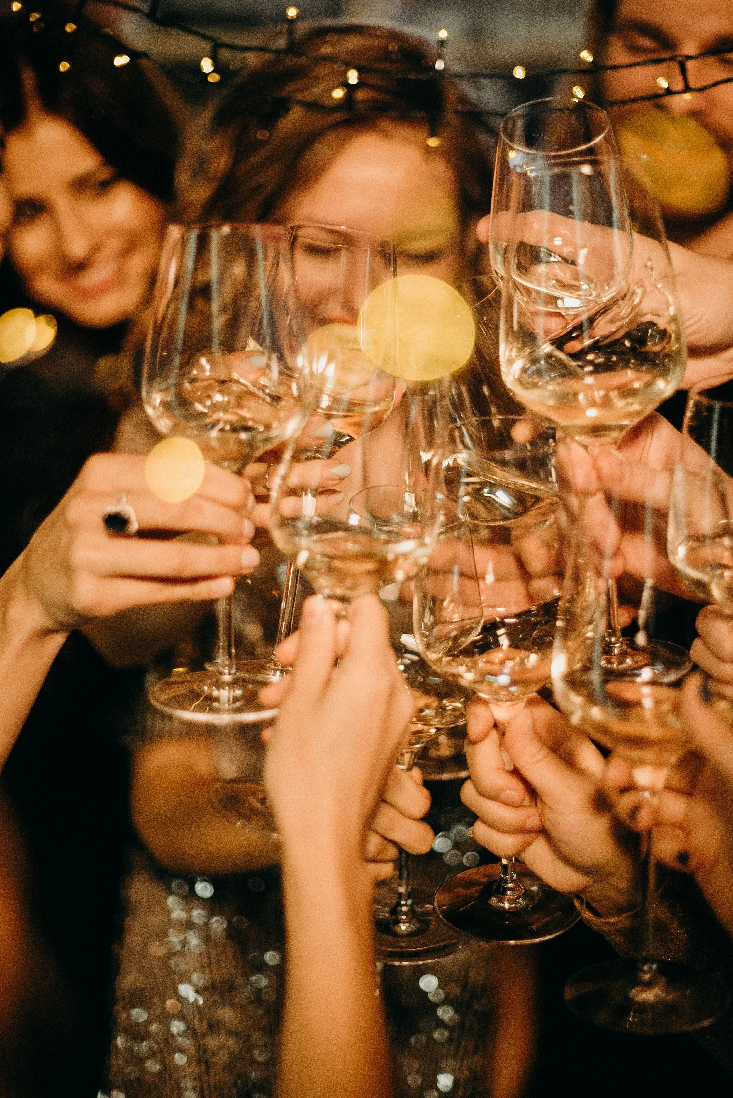A group of people raising glasses of white wine for a toast at a celebration or party.