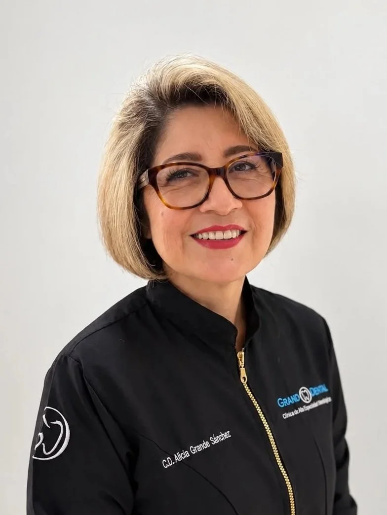 Mujer con cabello rubio y corte de cabello bob, lleva una chaqueta azul con logotipo y texto que dice 'Ceci de la Cruz', de pie contra un fondo blanco.