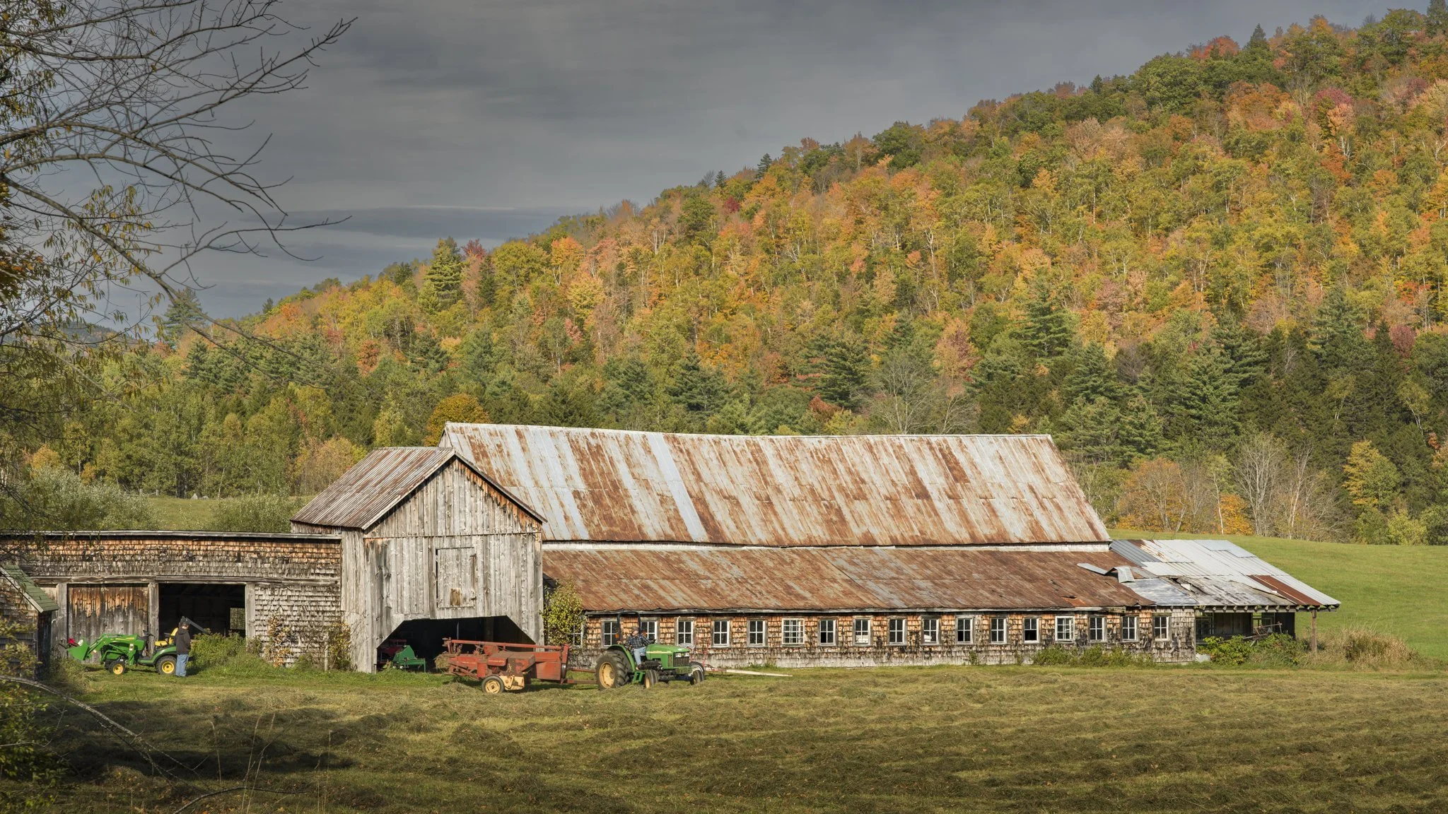 Tractors at rest under a rusty roof.