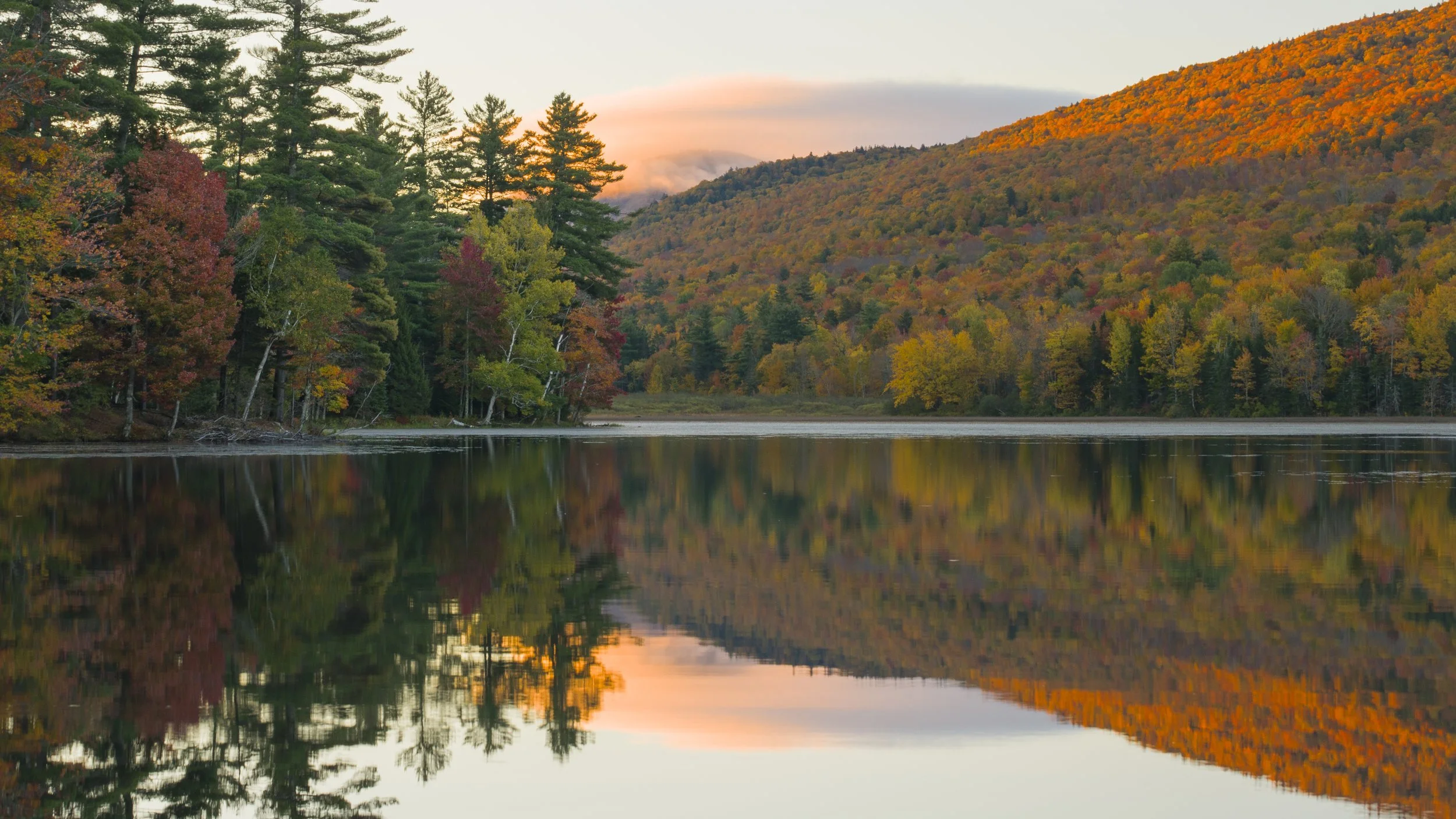 First light doubles itself on a glass-calm lake.