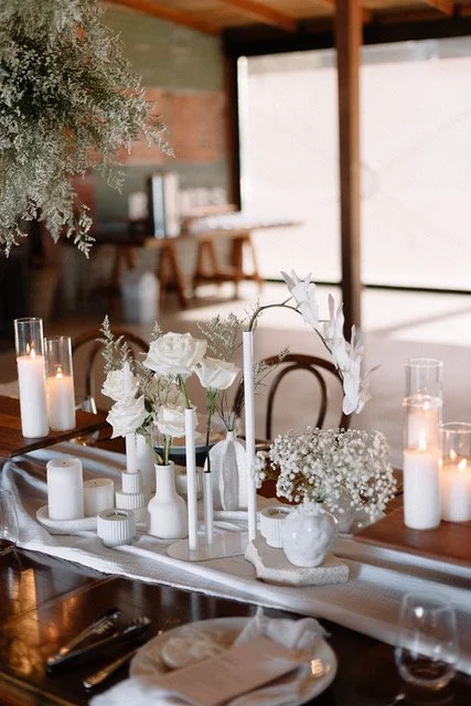 Elegant dining table decorated with white flowers and candles in a cozy, warmly lit interior.