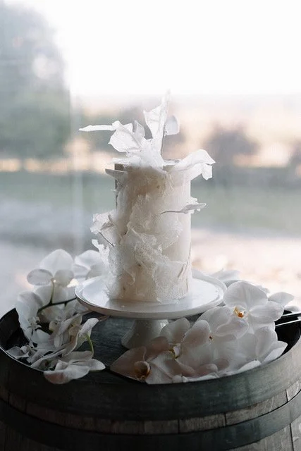 A decorative candle surrounded by white orchid flowers on a tray.