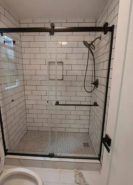Remodeled shower with white subway tile and a glass door