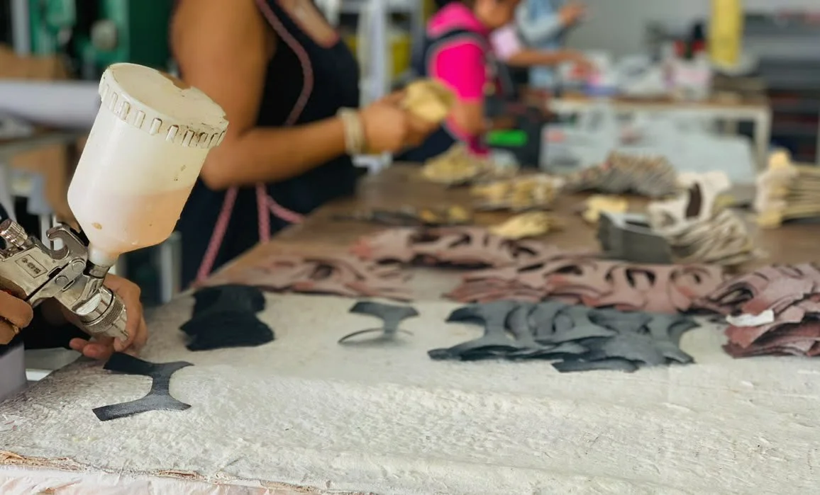 Worker using a spray gun to apply paint to fabric pieces in a garment workshop