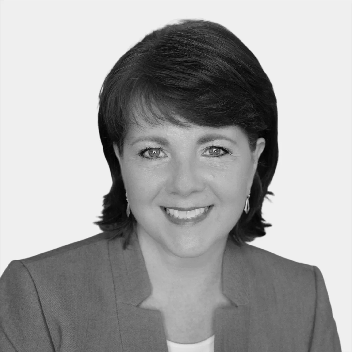 Black and white portrait of a woman with short, dark hair, smiling, wearing earrings and a blazer.