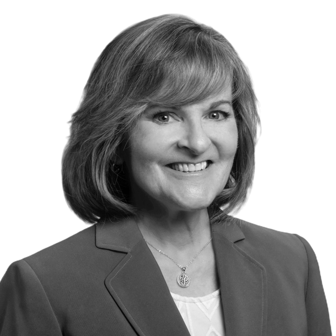 Black and white headshot of a woman with shoulder-length hair, wearing a blazer and a necklace, smiling at the camera.