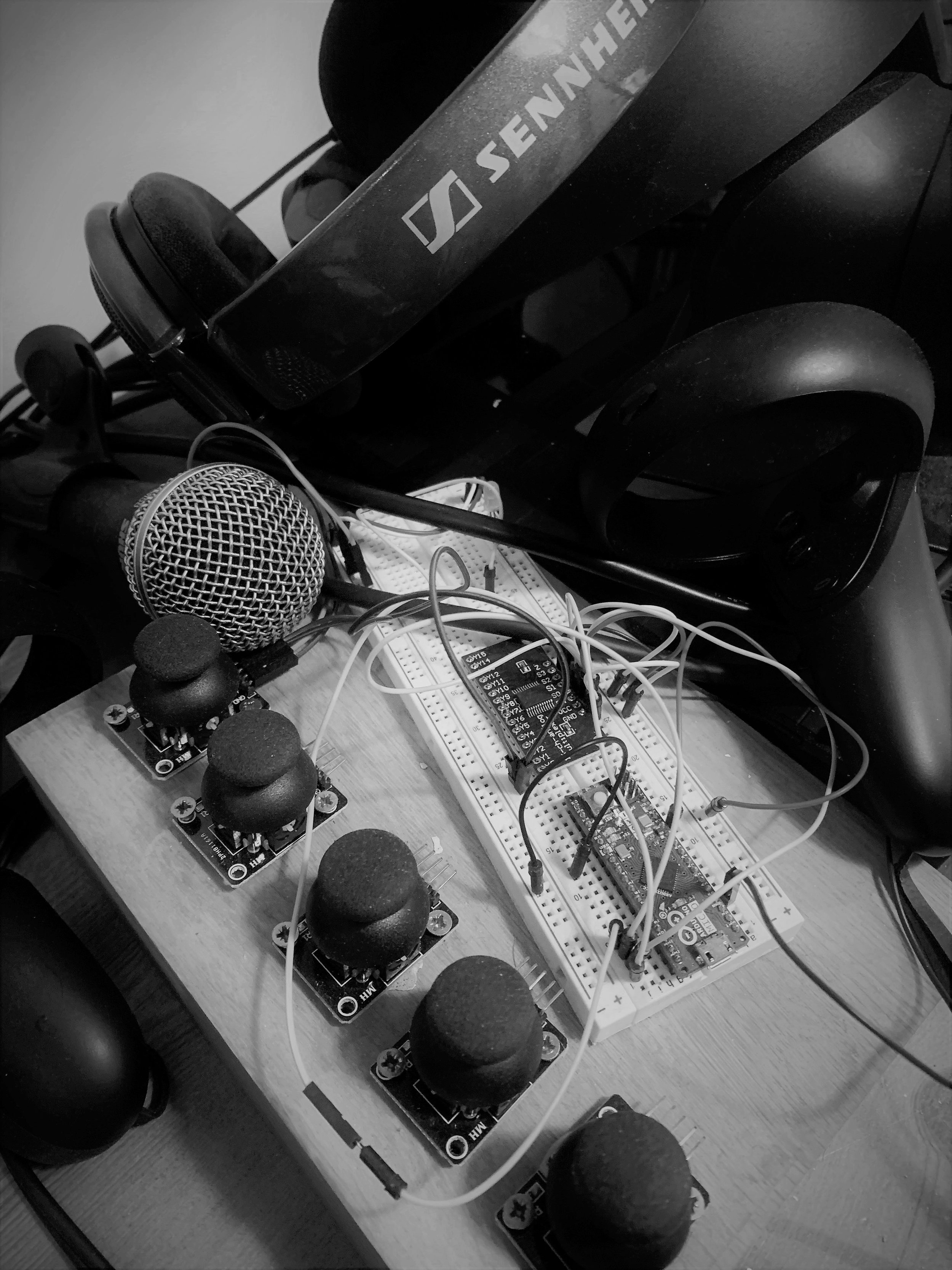 Electronic components including multiple microphones, sennheiser headphones, a breadboard, an Arduino microcontroller, and wires arranged on a wooden table.