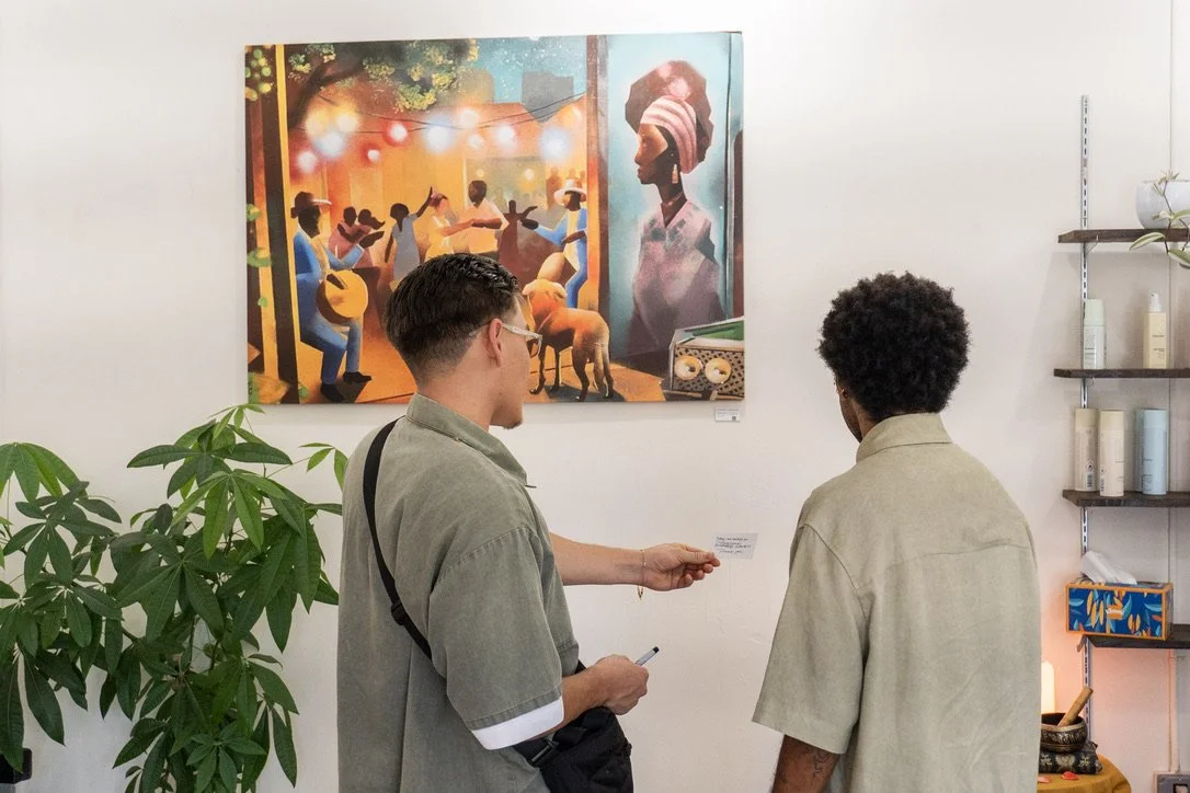 Two young men at an art gallery, looking at a colorful painting of a lively outdoor scene with people dancing, playing music, and a large portrait of a woman wearing a headwrap.