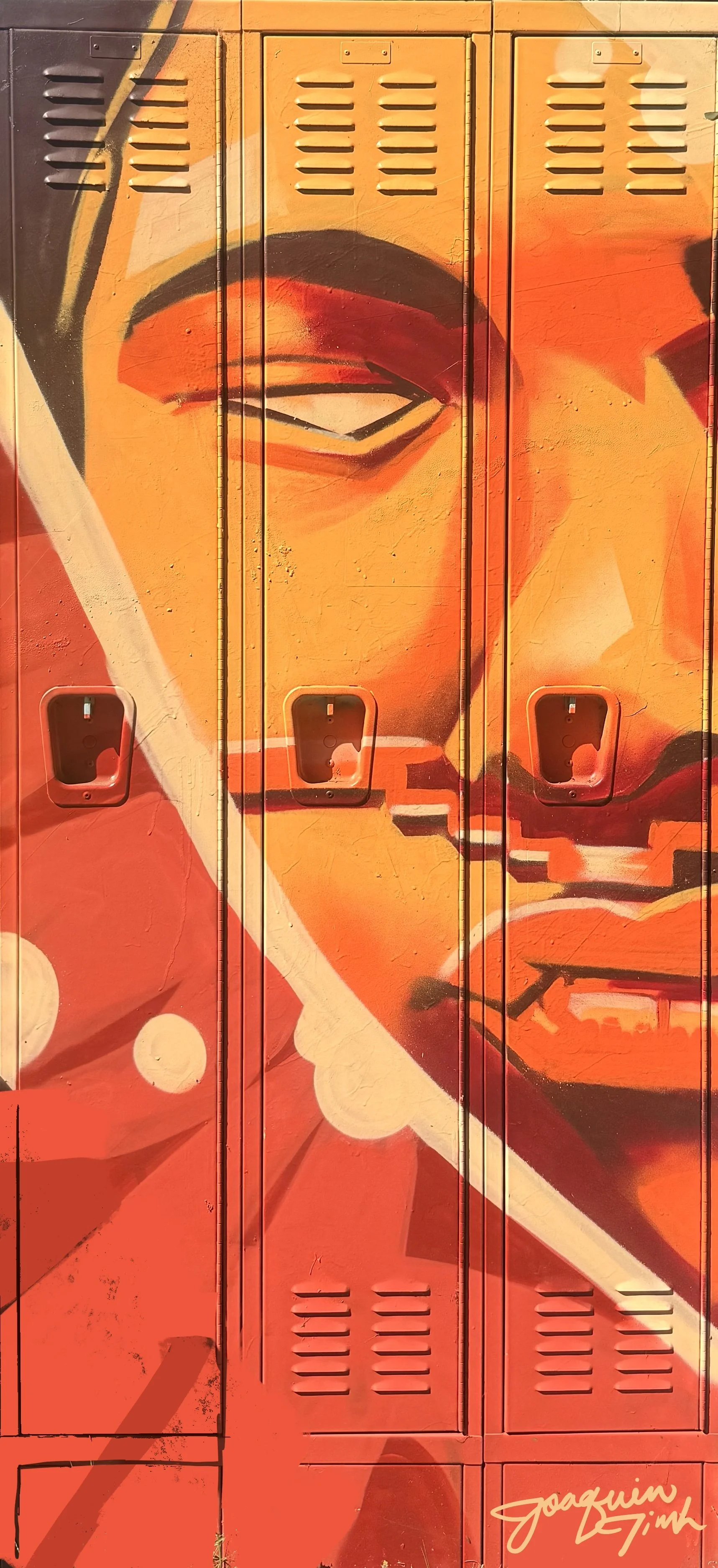 Colorful graffiti art of a person's face on a row of school lockers, signed by Joachim Zink.