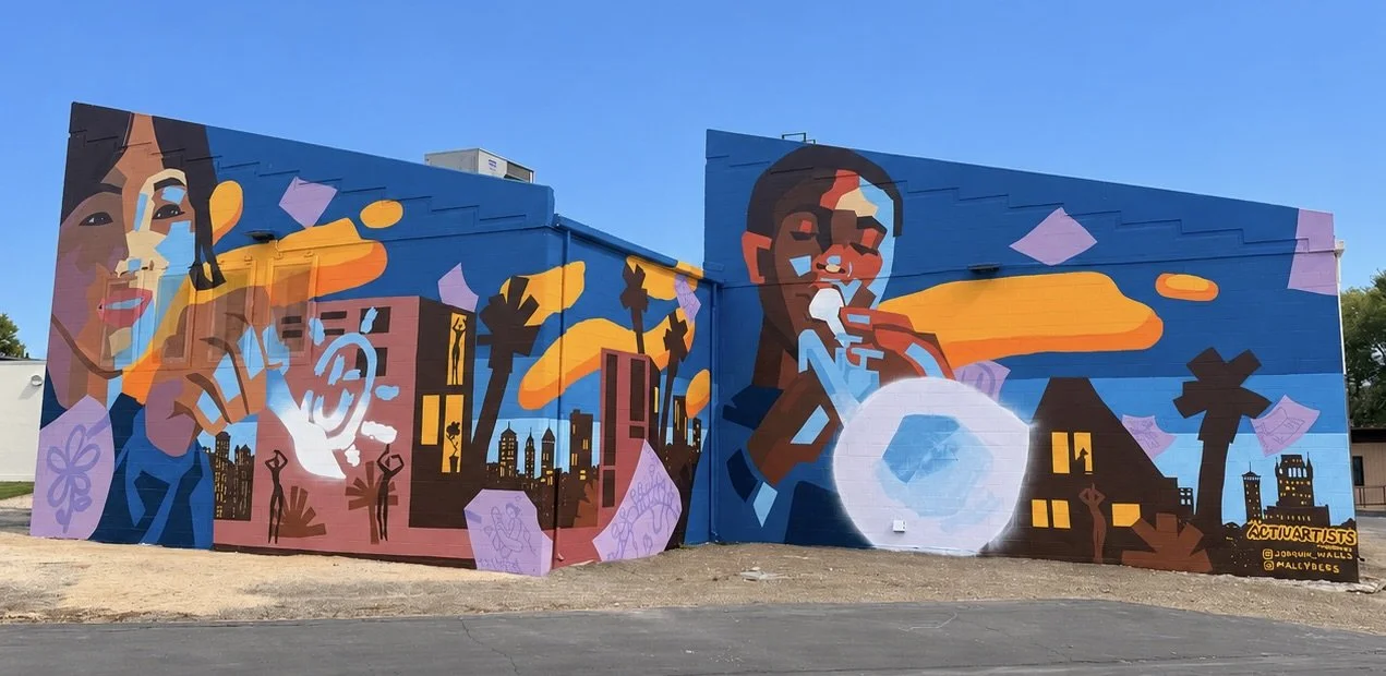 Colorful mural featuring two stylized women, cityscape with palm trees, clouds, and abstract shapes, in vibrant blue, orange, purple, and brown tones.
